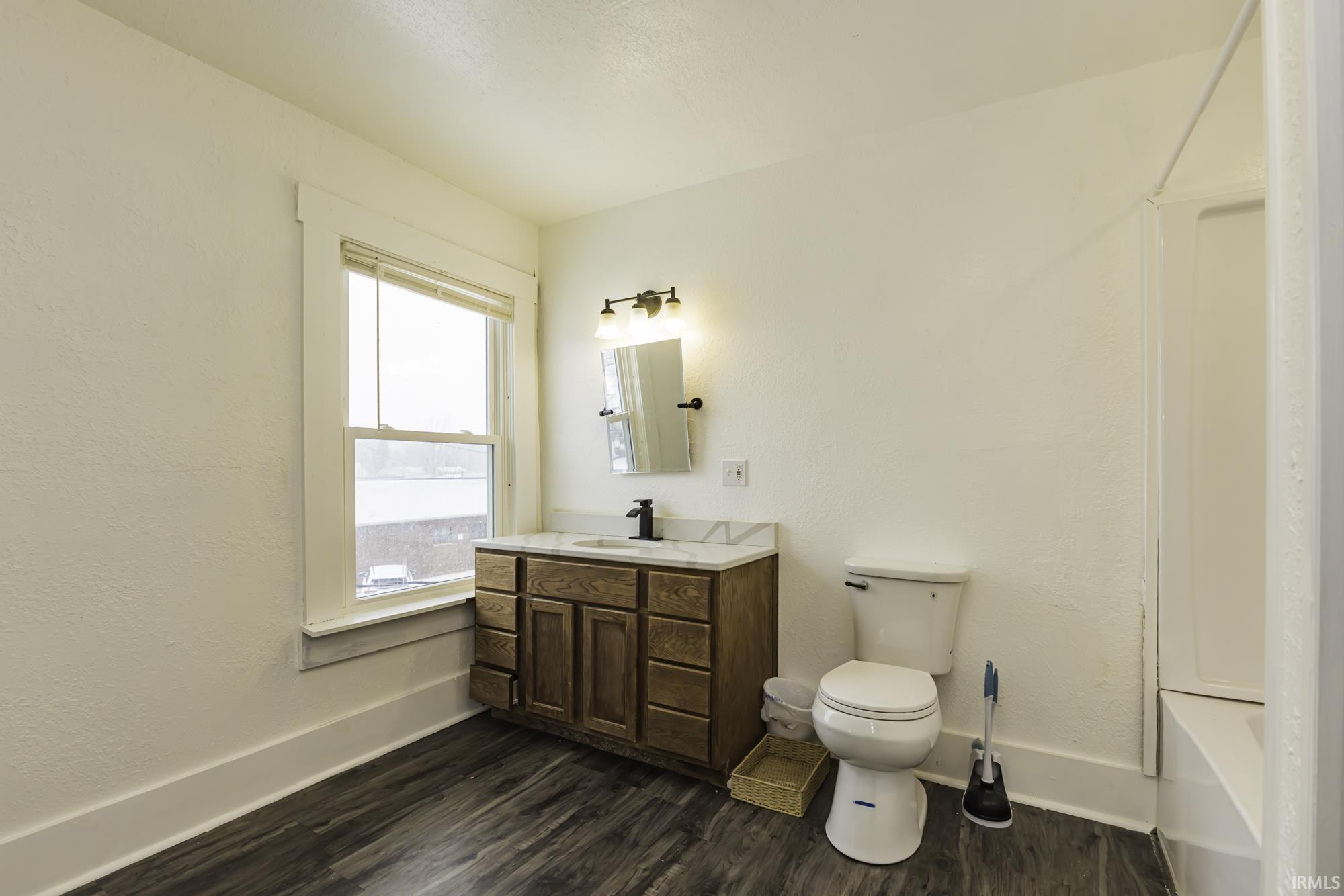 Full bathroom featuring dark wood finished floors, vanity, bathtub / shower combination, and a textured wall