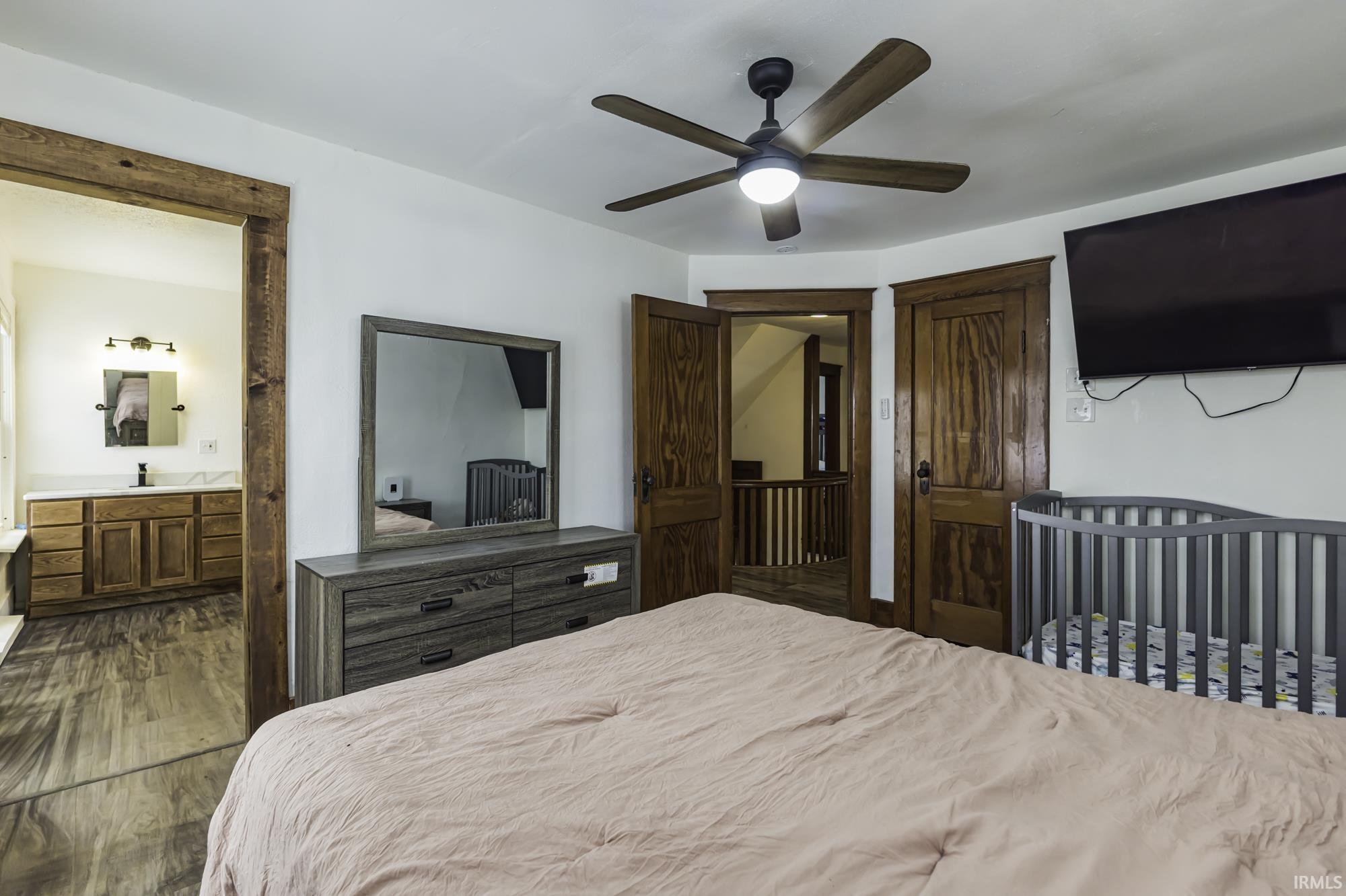 Bedroom with dark wood-type flooring, a ceiling fan, and ensuite bathroom
