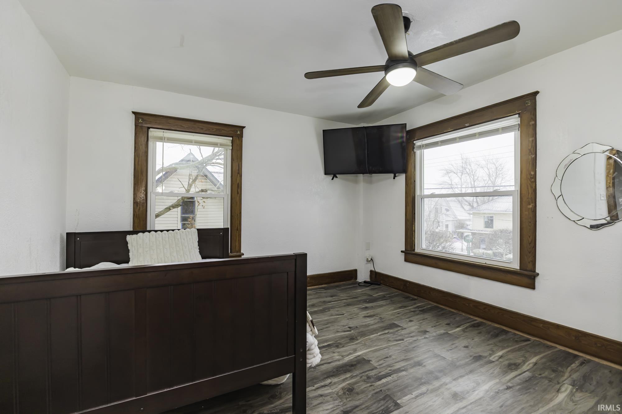 Bedroom with a ceiling fan, multiple windows, and dark wood-type flooring