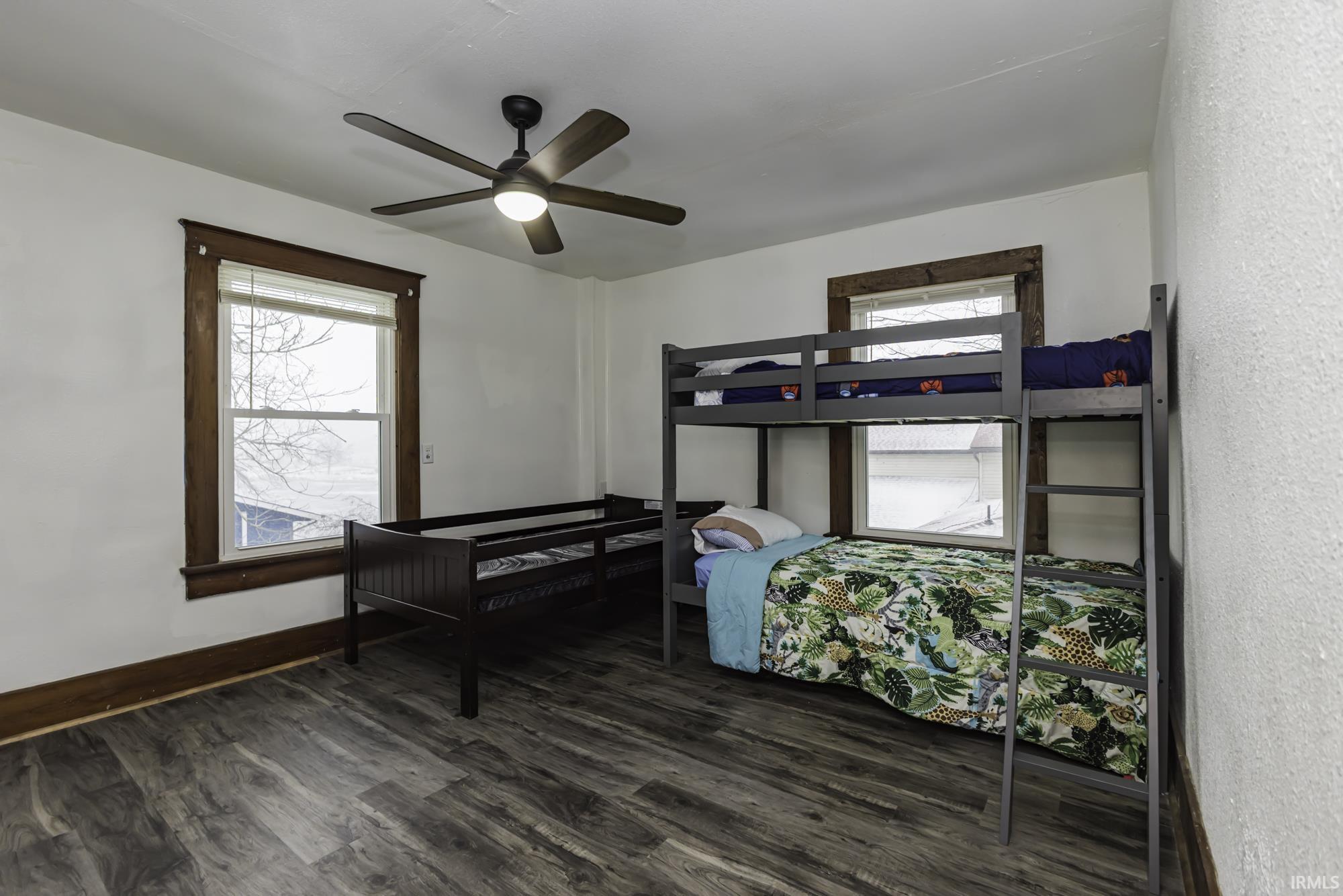 Bedroom featuring a ceiling fan, dark wood-style flooring, and multiple windows