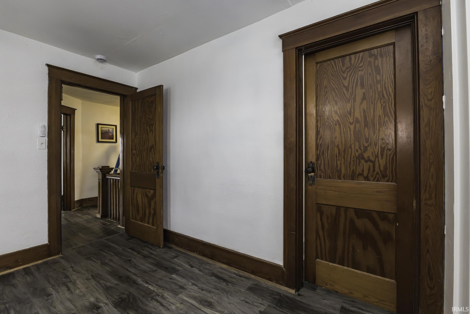 Empty room with baseboards and dark wood-style flooring
