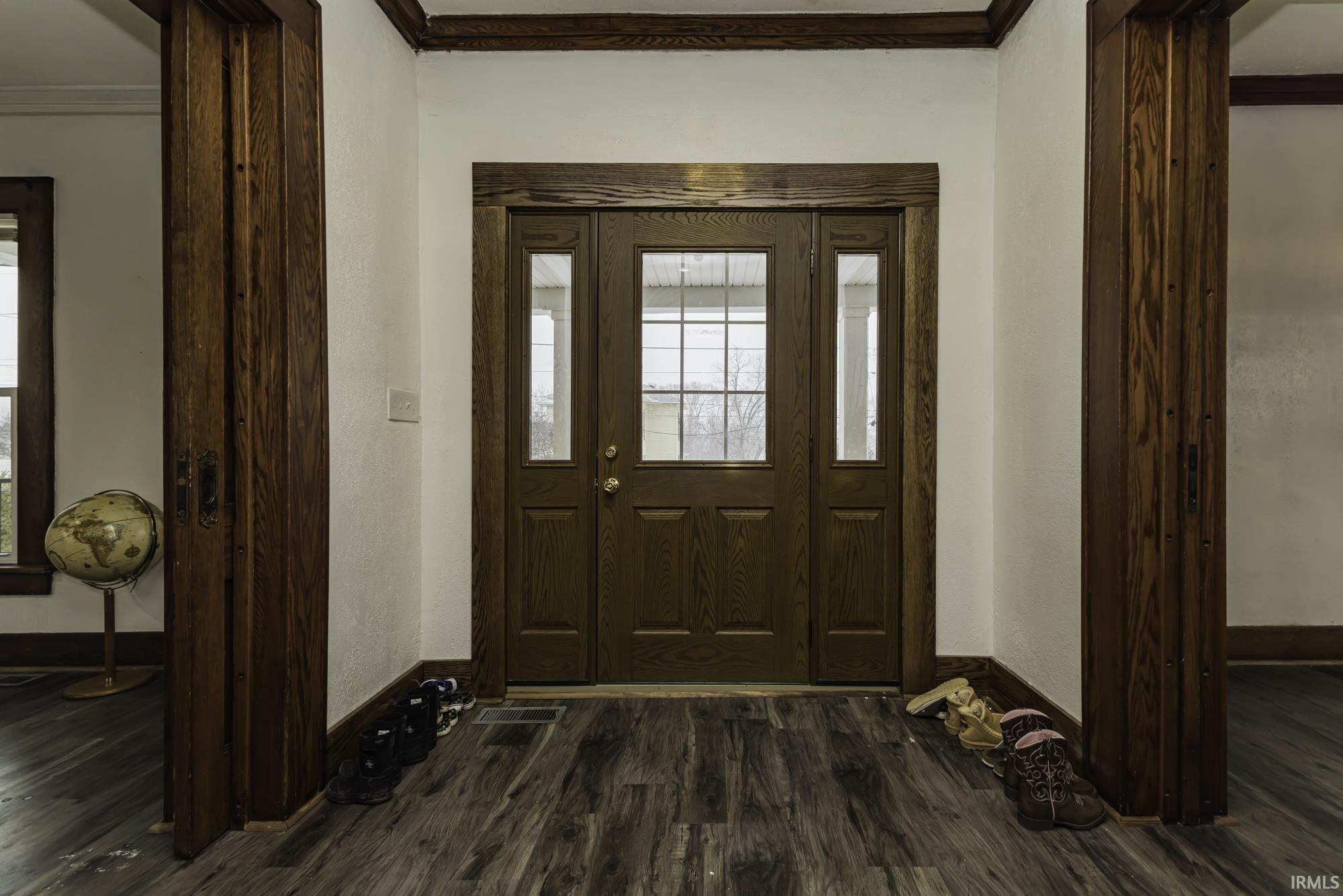 Entryway with dark wood-type flooring and ornamental molding