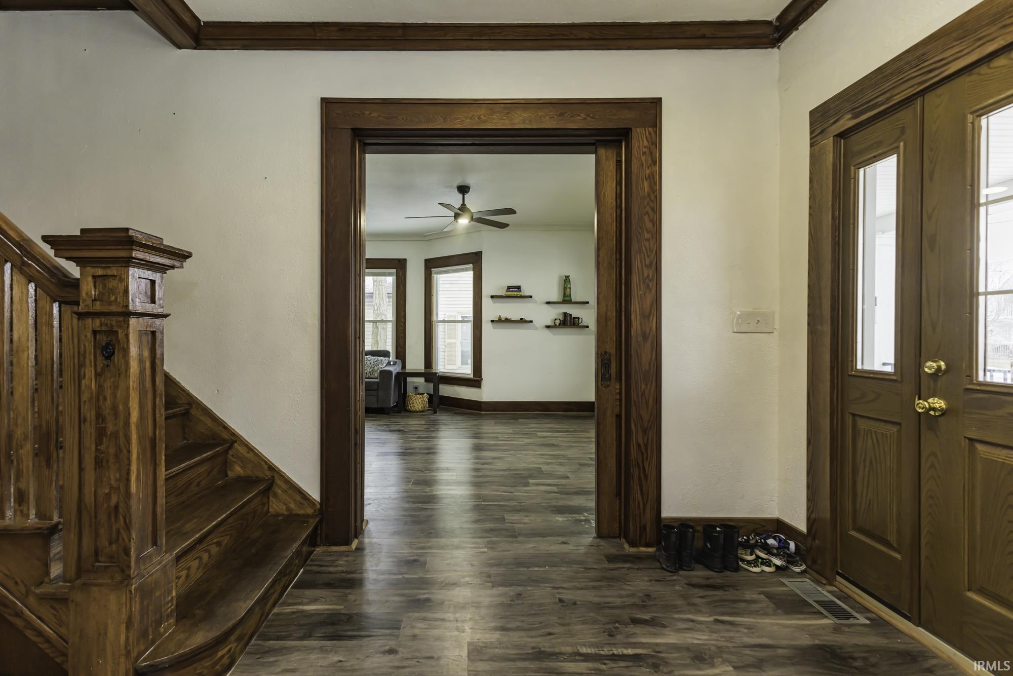 Entryway featuring ornamental molding, stairway, dark wood-style flooring, and ceiling fan
