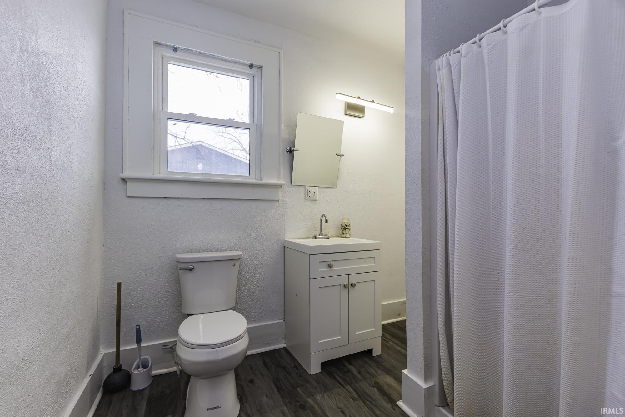 Bathroom with a shower with curtain, vanity, dark wood-type flooring, and a textured wall