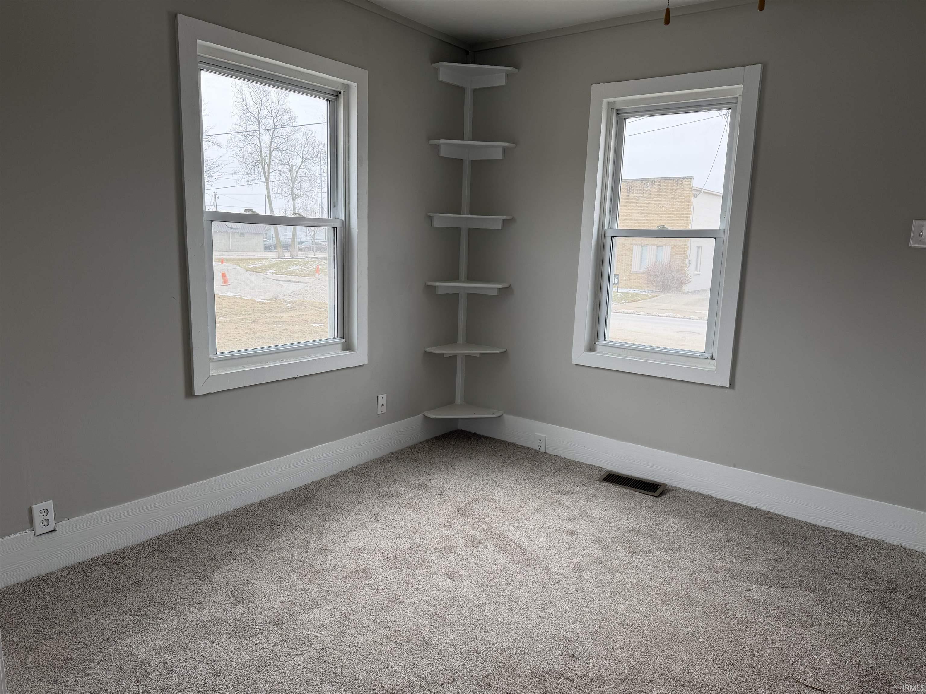 Carpeted spare room featuring healthy amount of natural light