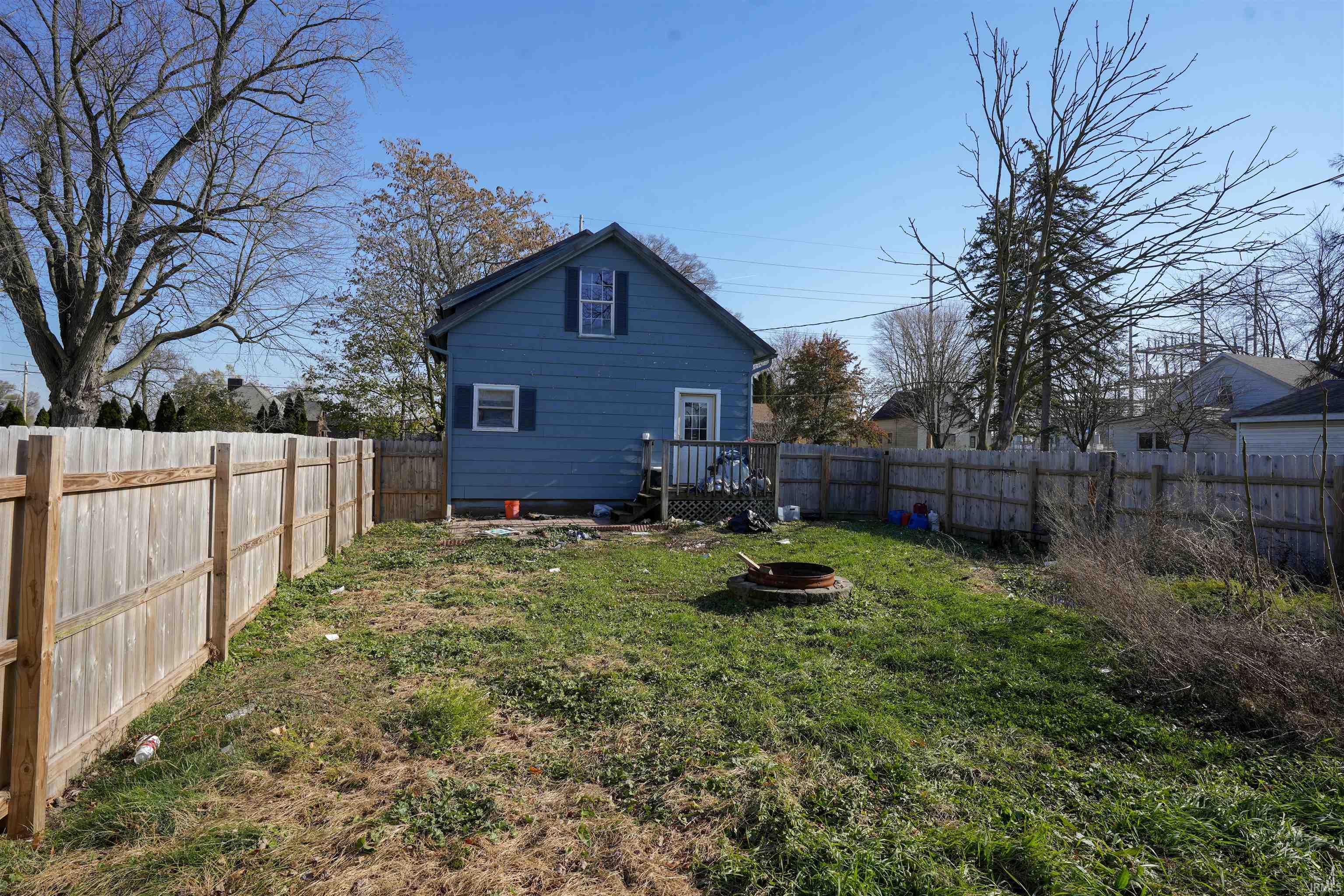 Rear view of property featuring an outdoor fire pit, a fenced backyard, and a deck