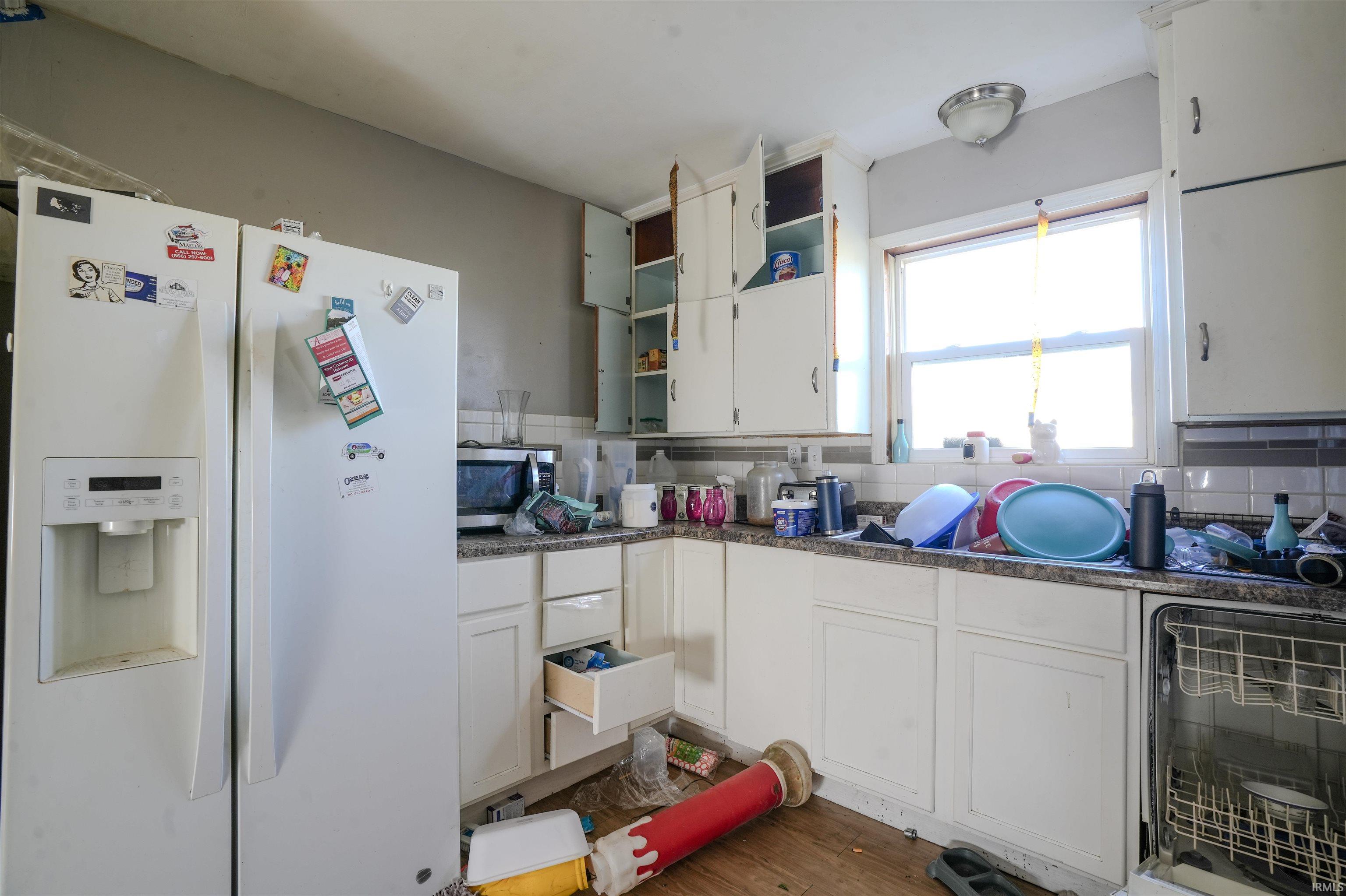 Kitchen with white fridge with ice dispenser, white cabinets, open shelves, backsplash, and dishwasher