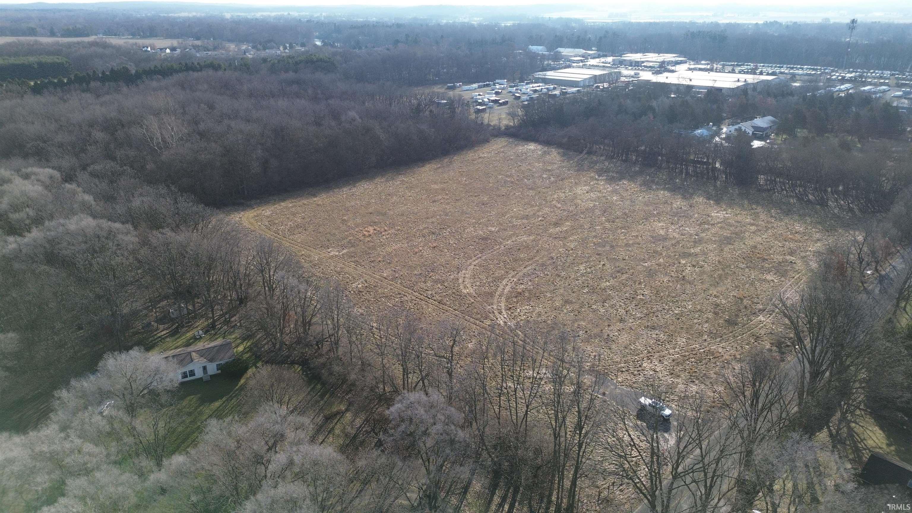 Aerial view of property and surrounding area featuring rural landscape and a heavily wooded area