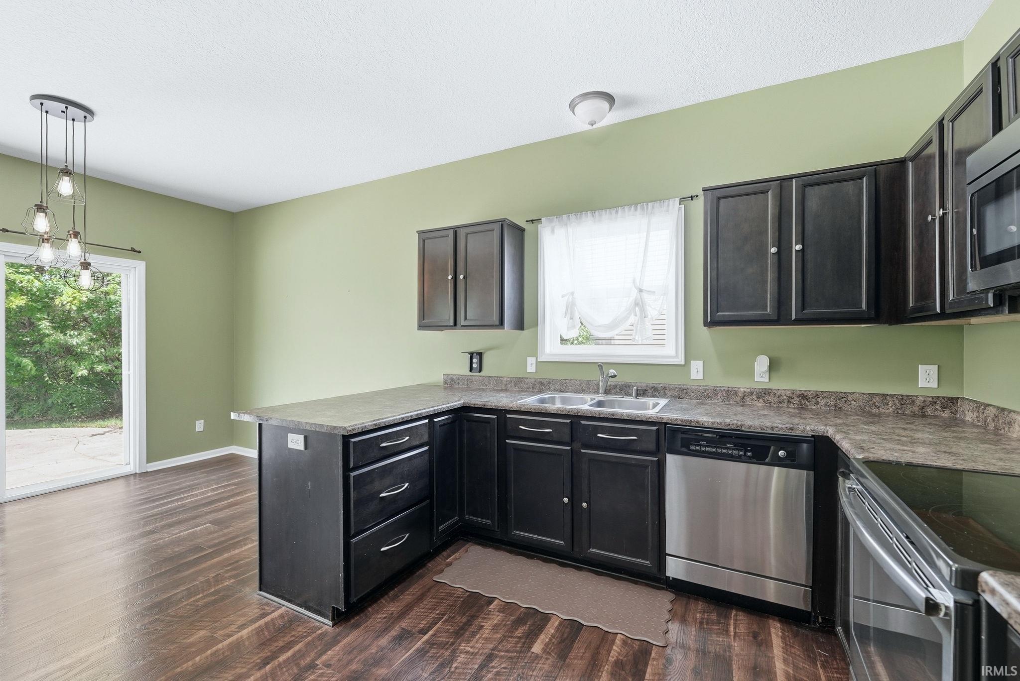 Kitchen featuring dark wood-finish cabinetry, stainless steel appliances, and wood-finish flooring