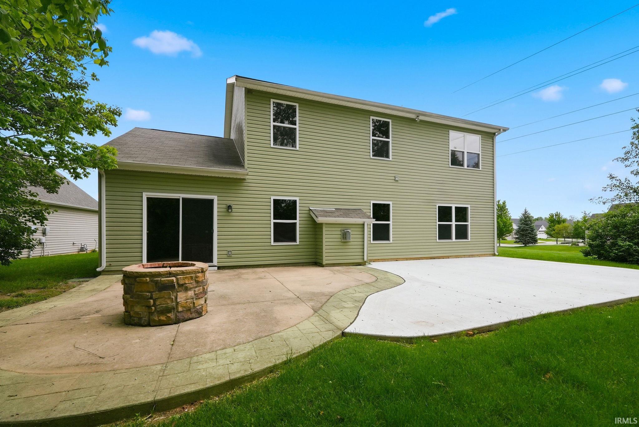 Expansive concrete patio featuring a stone fire pit, sliding glass door access, and a large additional paved area