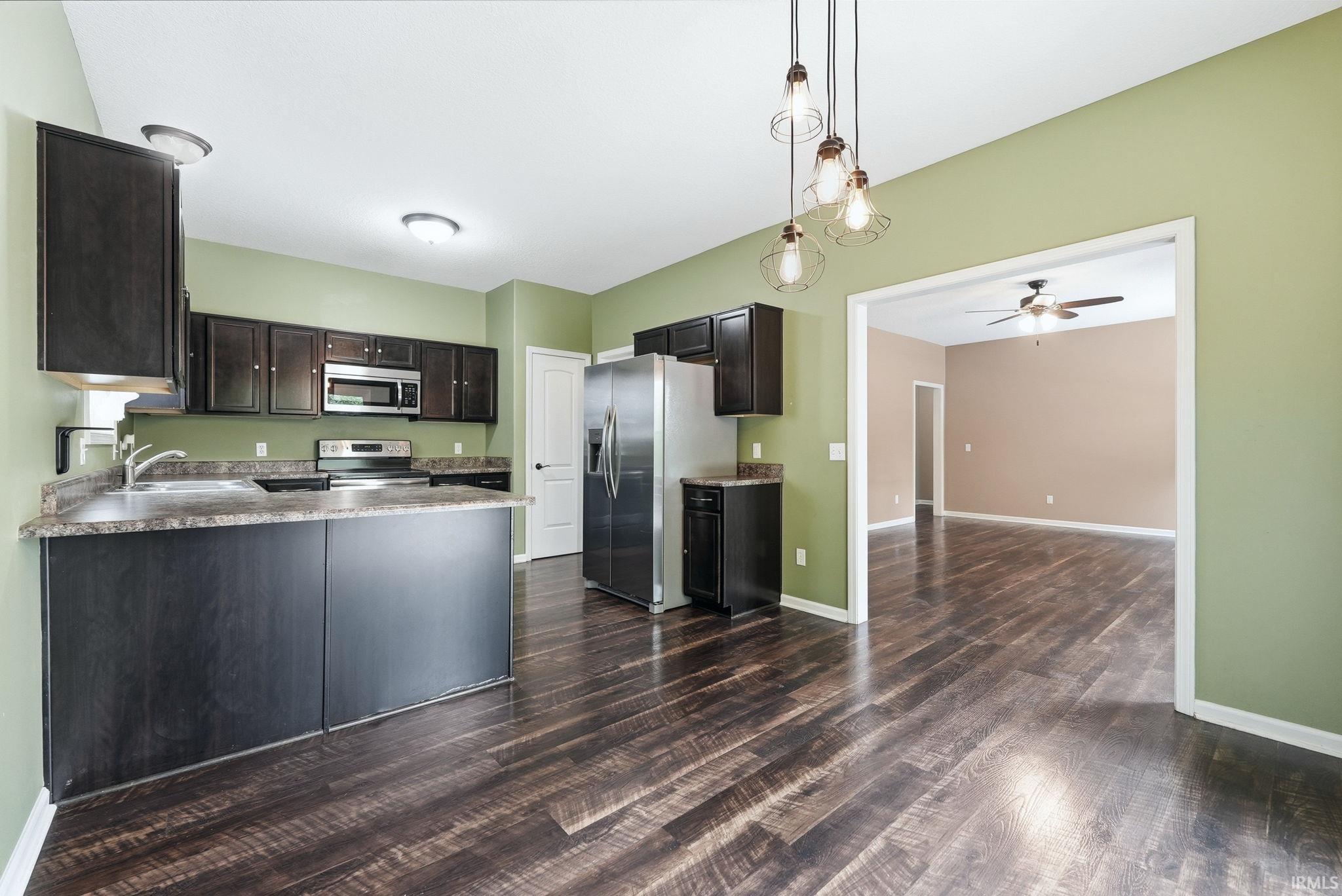 Kitchen featuring dark wood-finish cabinetry, stainless steel appliances, and wood-finish flooring