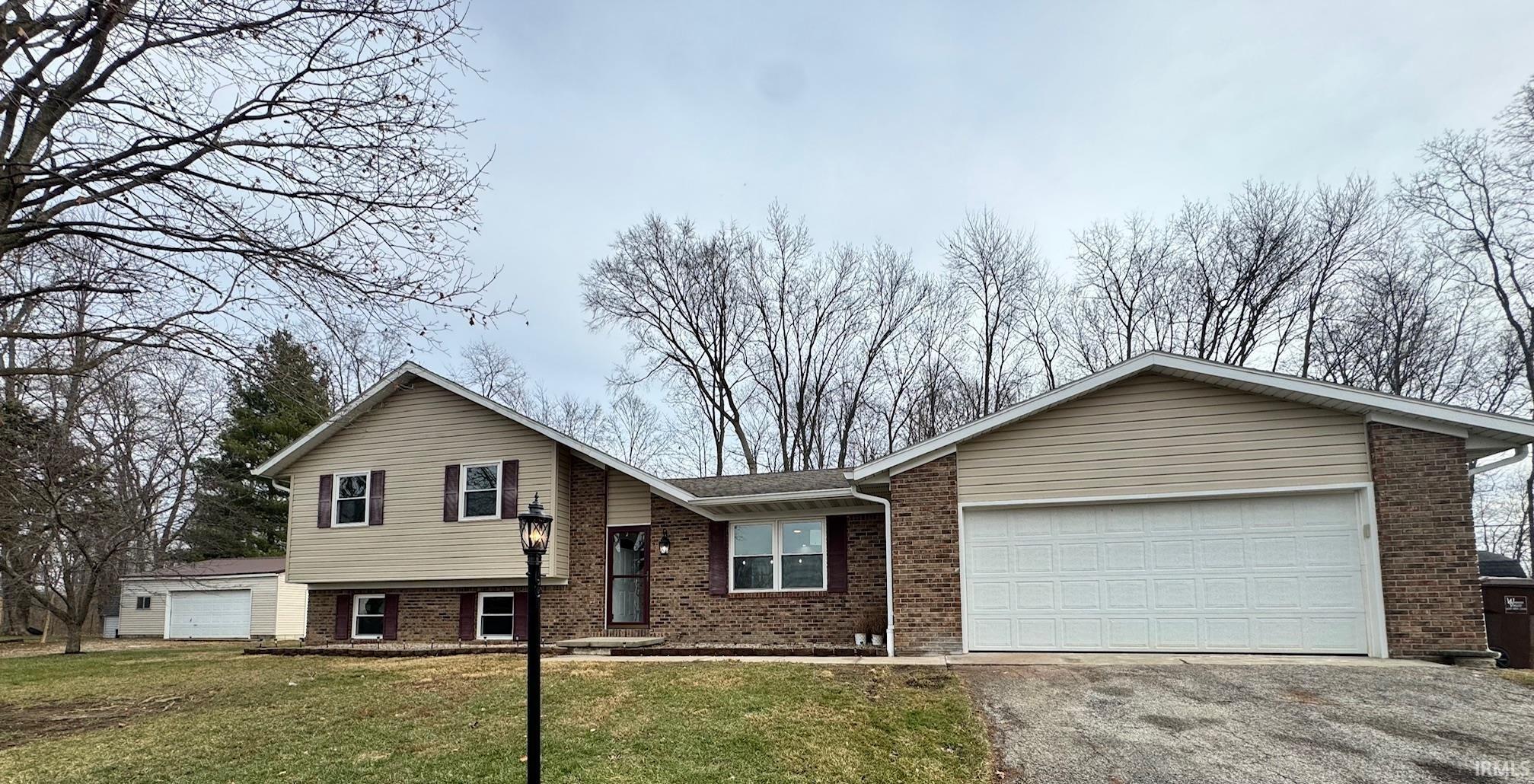 Split level home featuring brick siding, driveway, a front yard, and an attached garage
