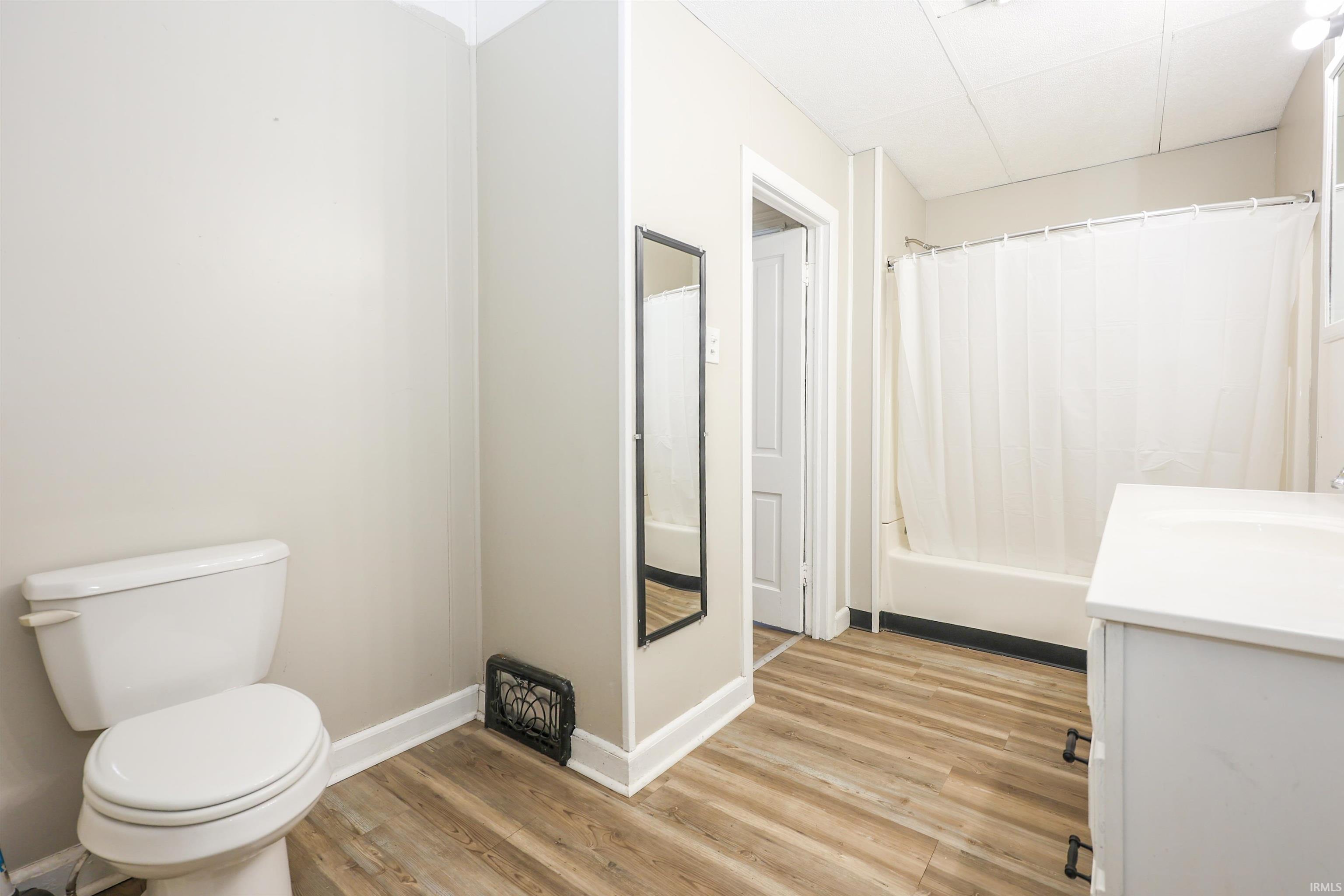 Bathroom with vanity, light wood finished floors, and shower / bathtub combination with curtain