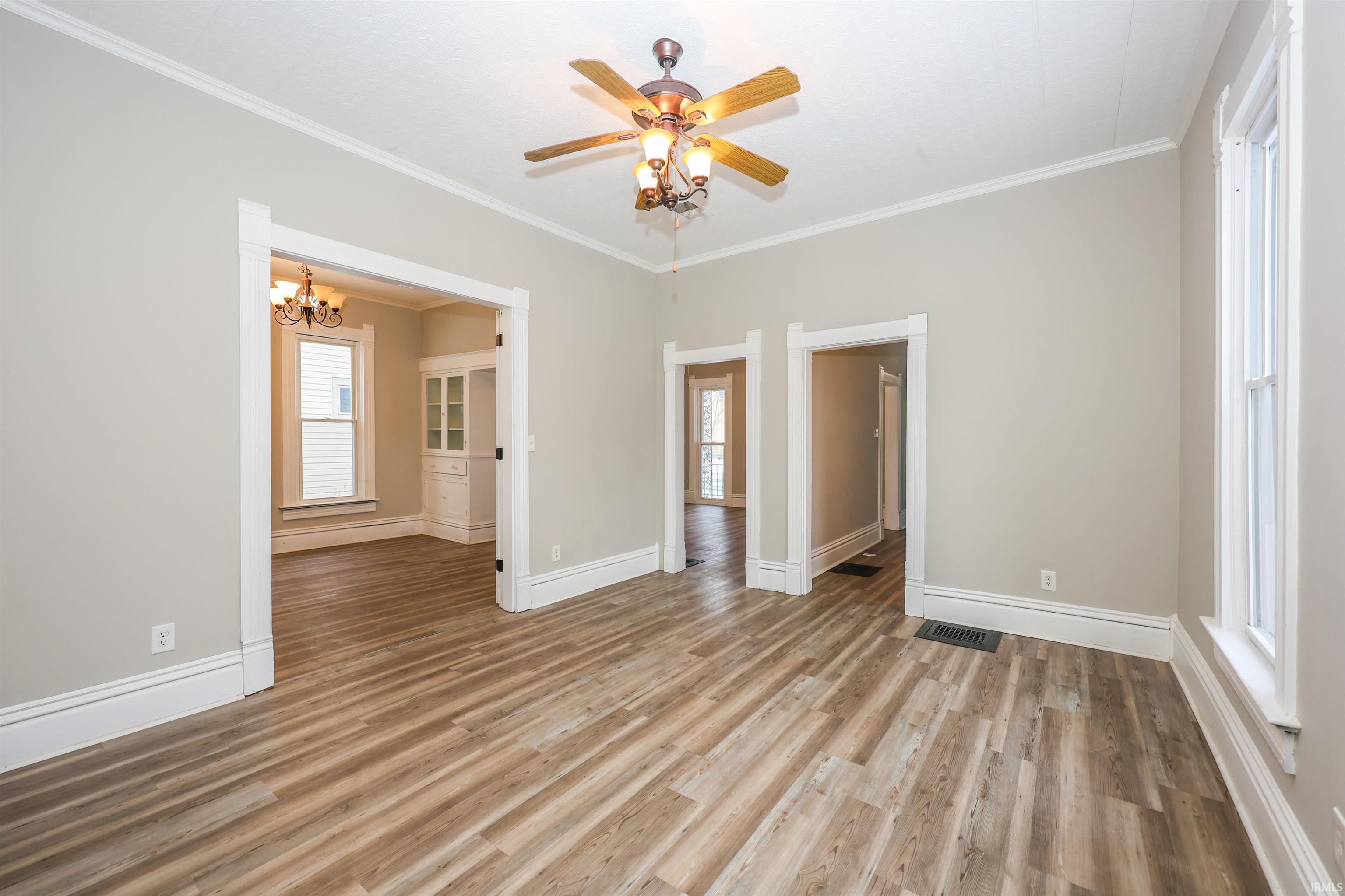 Unfurnished bedroom with ornamental molding, a chandelier, ceiling fan, and light wood-type flooring