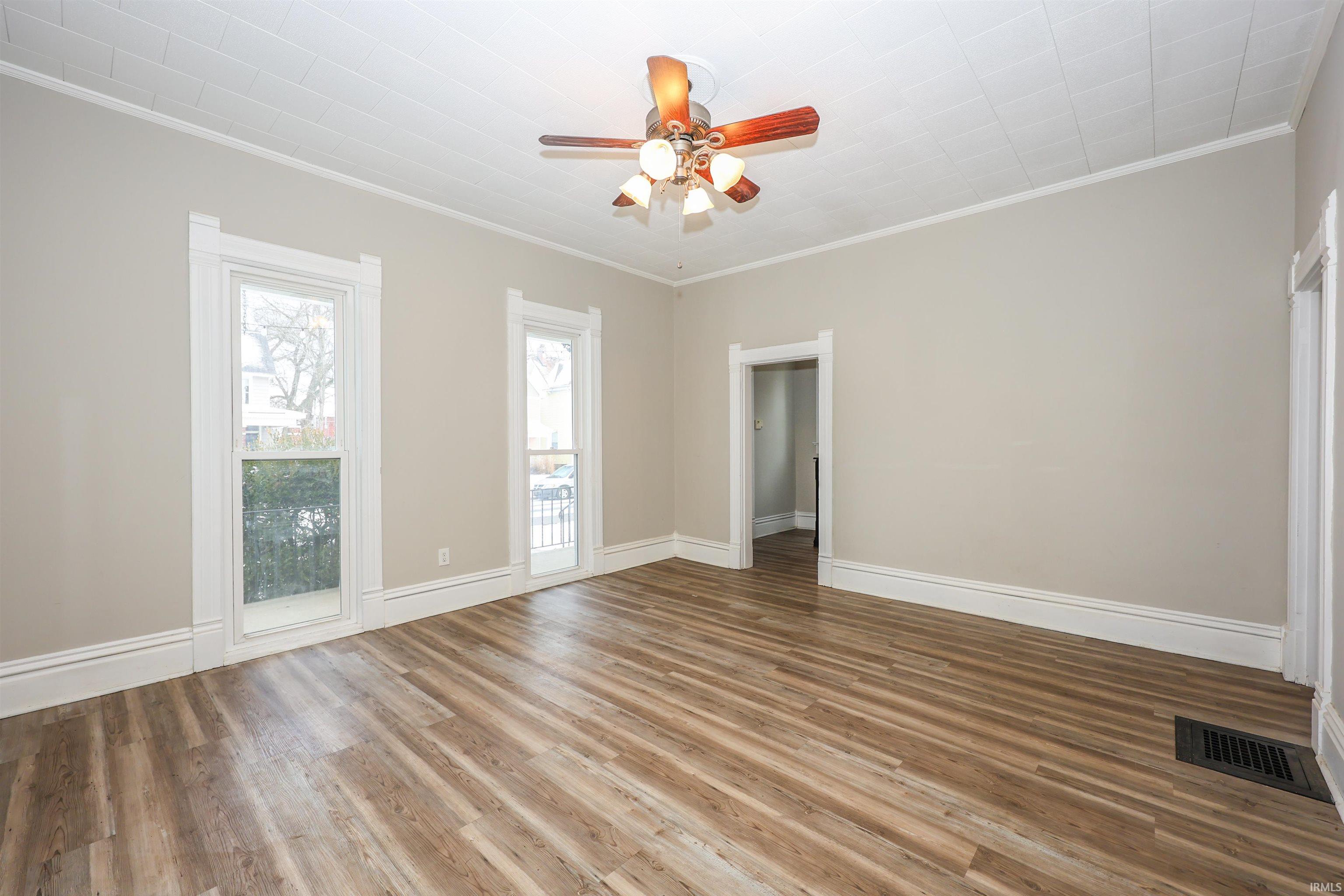 Unfurnished room with crown molding, light wood-type flooring, and a ceiling fan