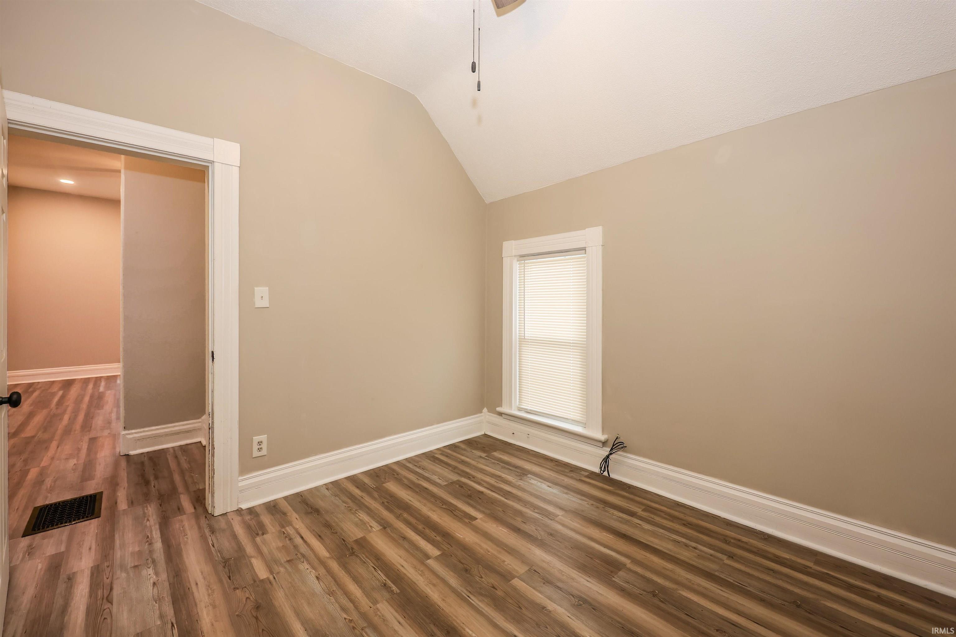 Unfurnished room featuring dark wood-style flooring, lofted ceiling, and ceiling fan
