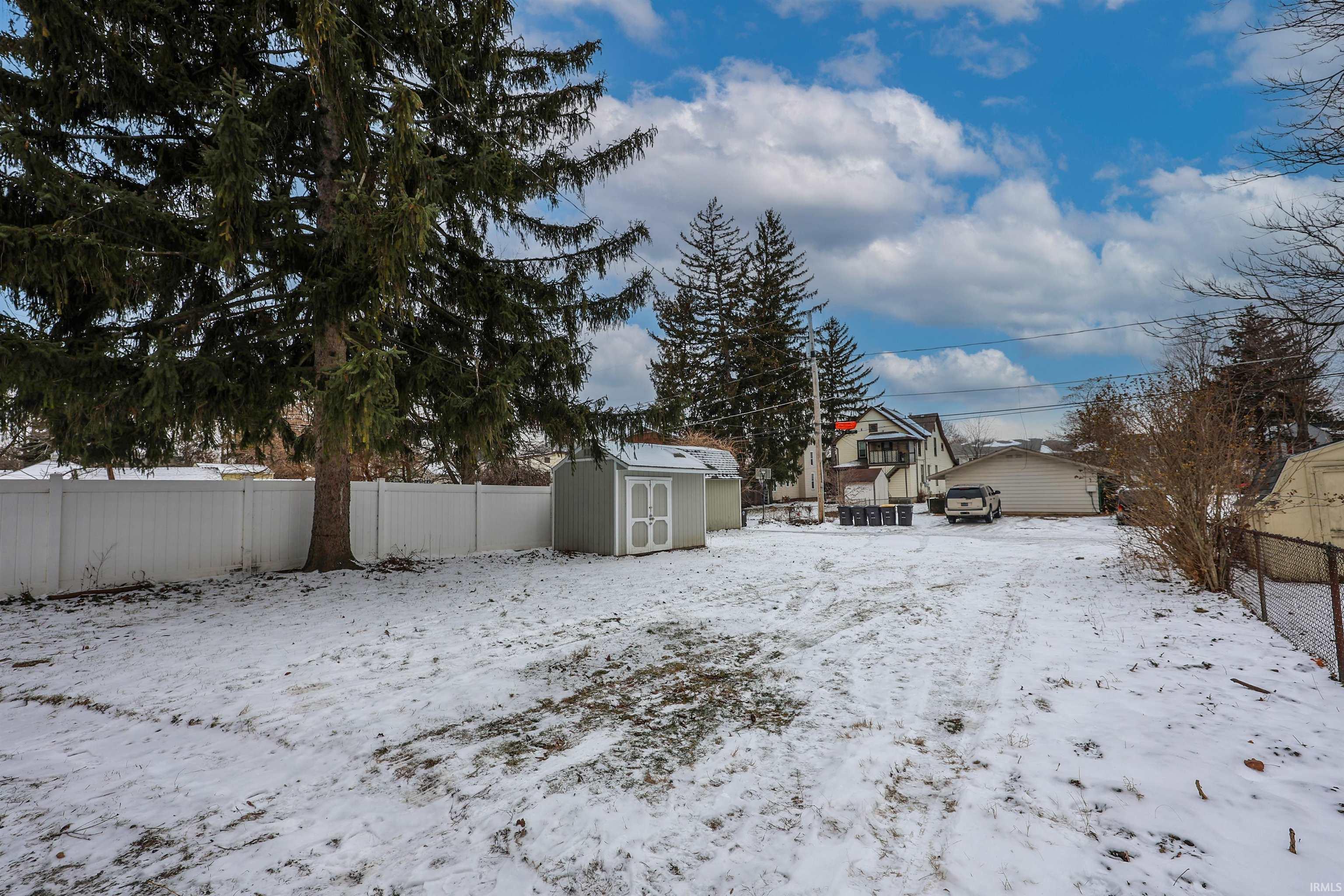 Yard covered in snow with a fenced backyard and a storage shed