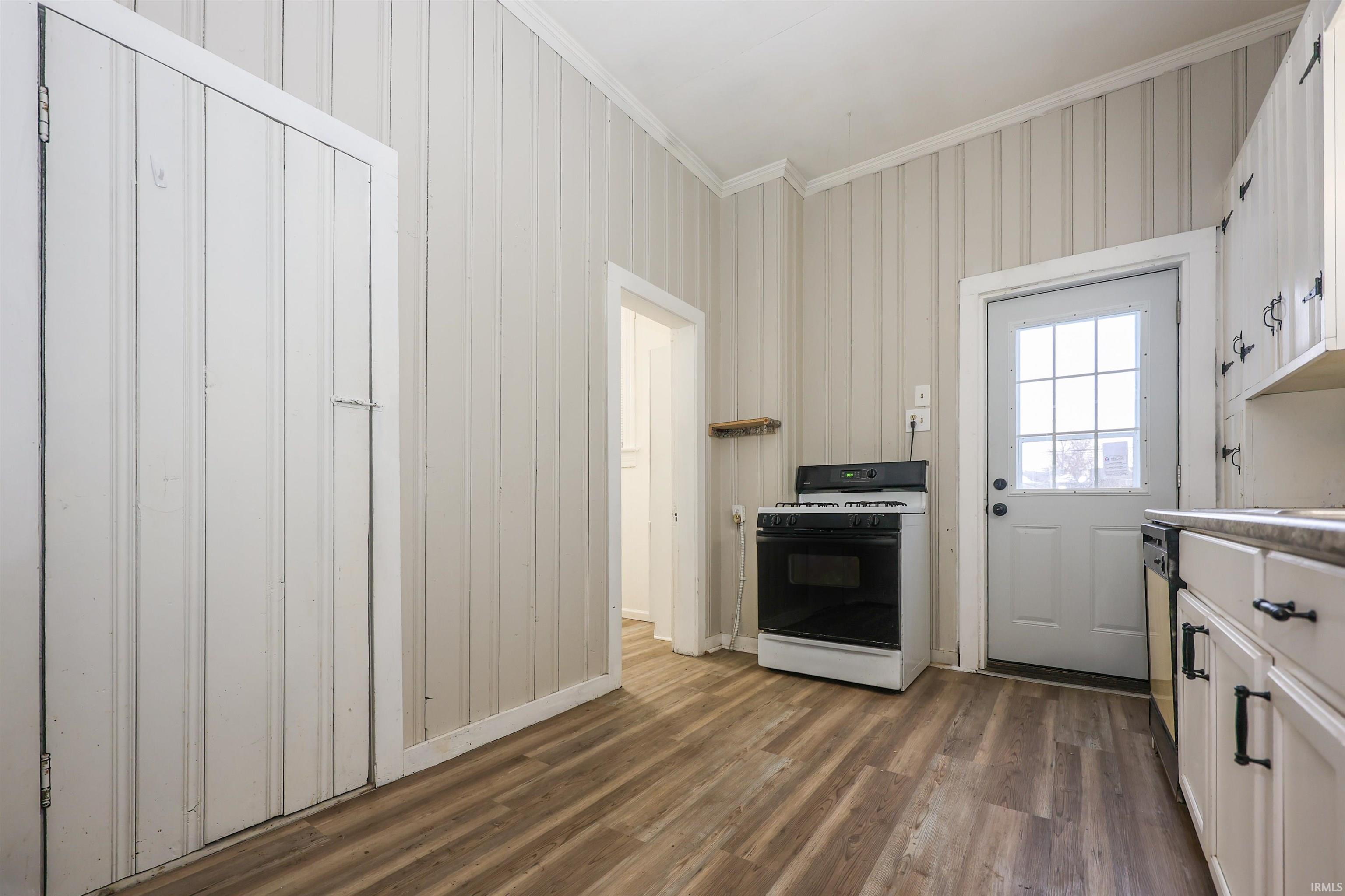Kitchen with range with gas stovetop, crown molding, dark wood-style floors, light countertops, and white cabinetry