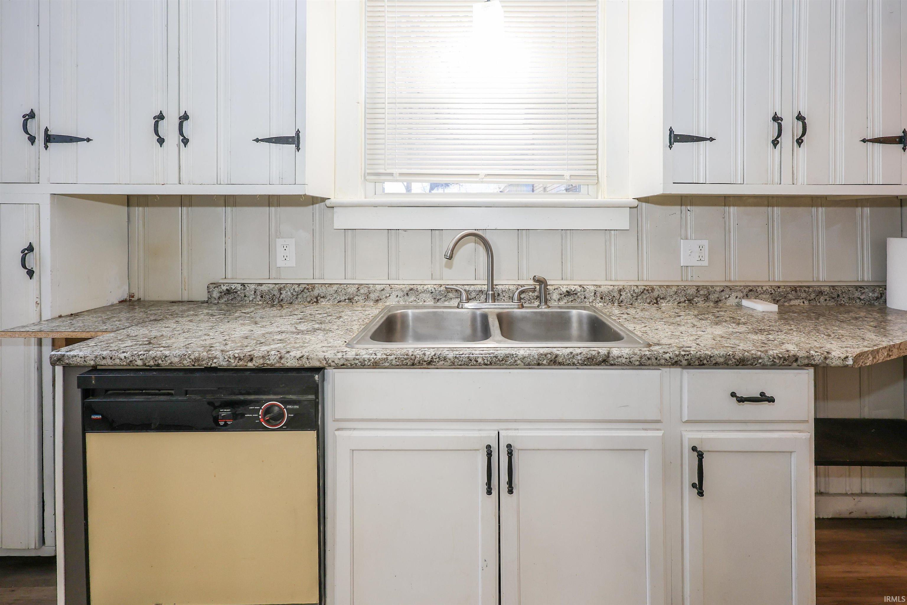 Kitchen with white cabinets, light countertops, and wood finished floors