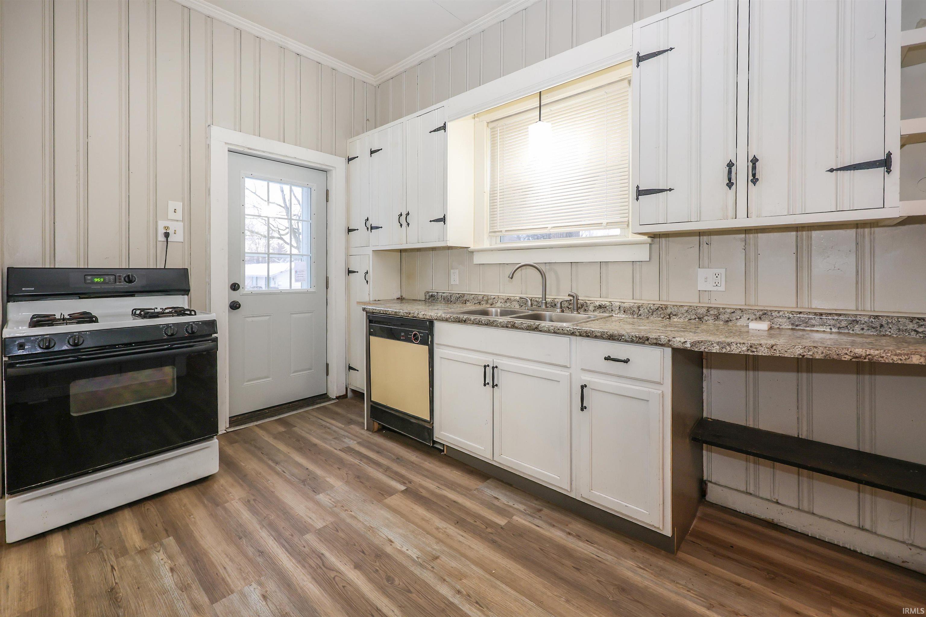 Kitchen featuring range with gas cooktop, ornamental molding, dishwasher, light wood-style flooring, and light countertops