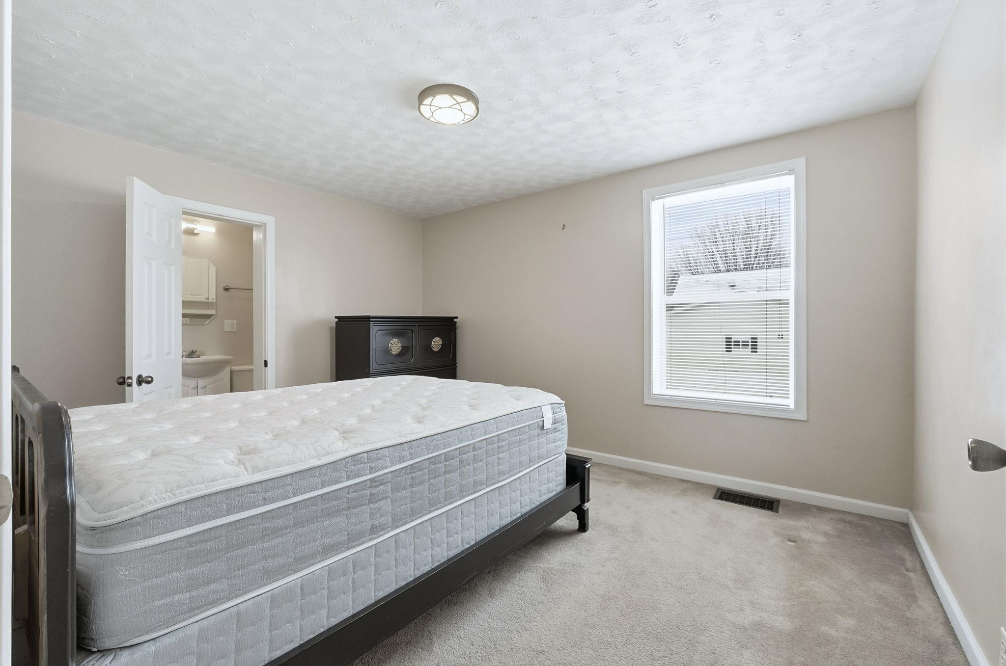 Carpeted bedroom featuring baseboards and a textured ceiling