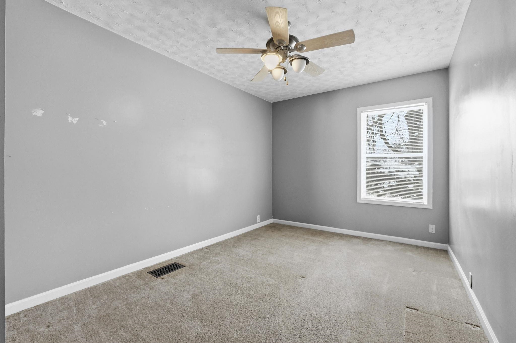 Spare room with light carpet, a textured ceiling, and a ceiling fan