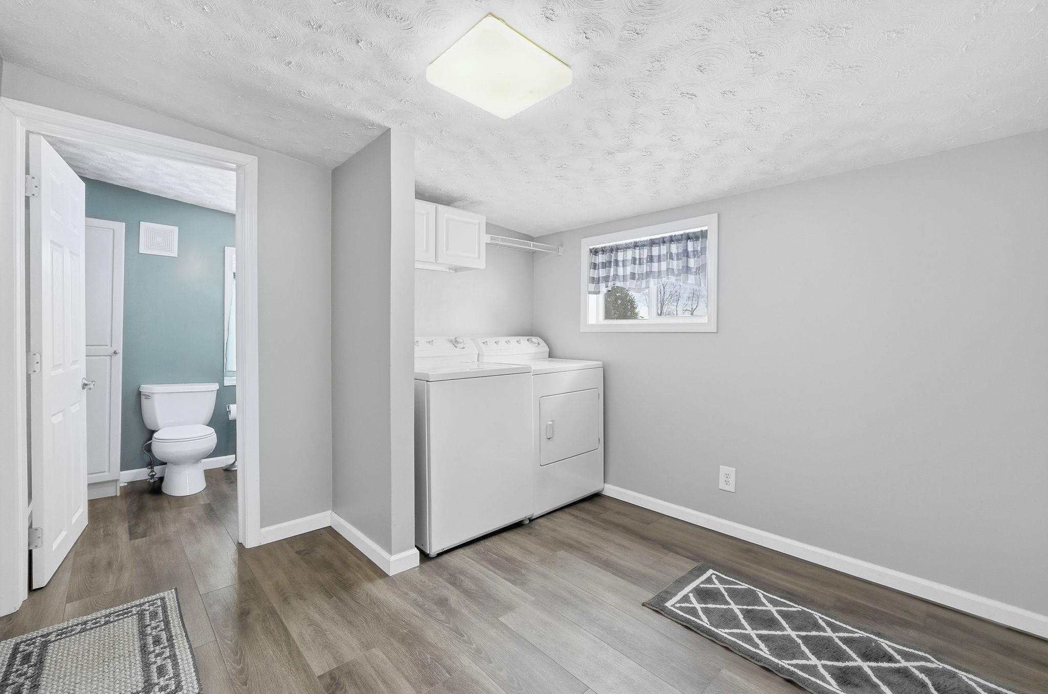 Large laundry/mudroom featuring a textured ceiling, wood finished floors, and independent washer and dryer