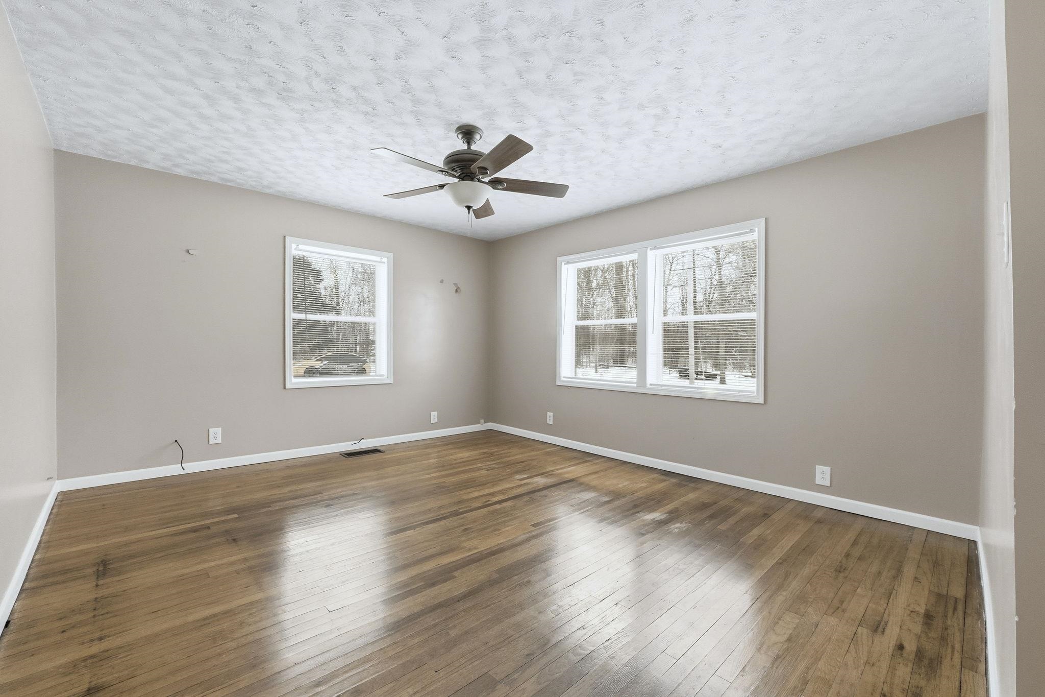 Living room with healthy amount of natural light, a textured ceiling, hardwood floors, and a ceiling fan