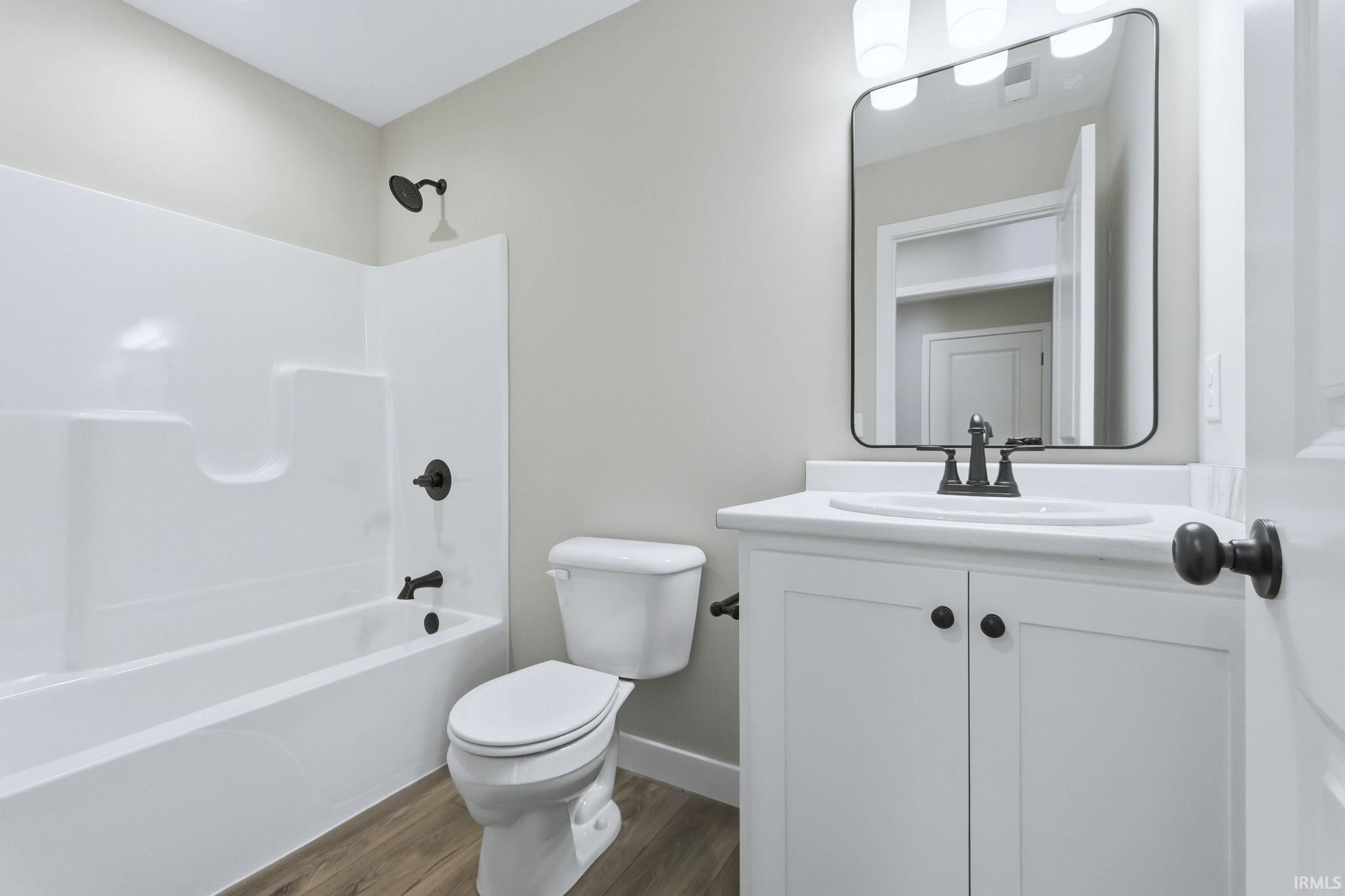 Full bathroom with shower / bathtub combination, vanity, and dark wood-style flooring