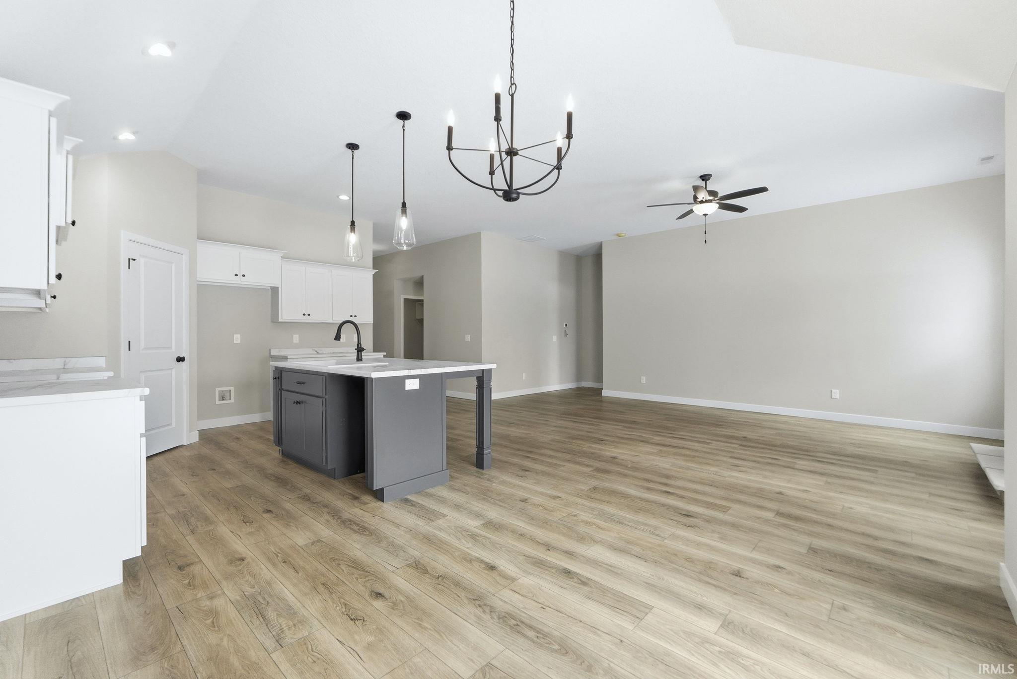 Kitchen with gray cabinetry, a chandelier, a kitchen bar, white cabinetry, and a center island with sink