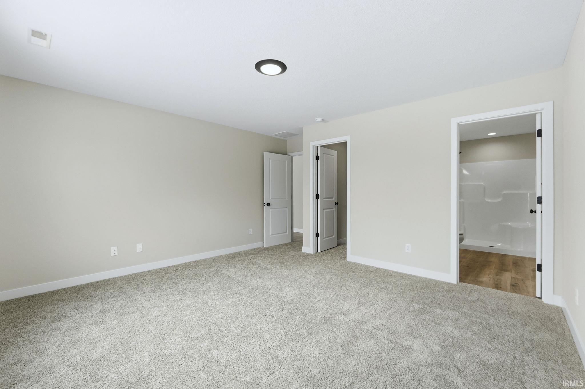 Unfurnished bedroom with light colored carpet and ensuite bath