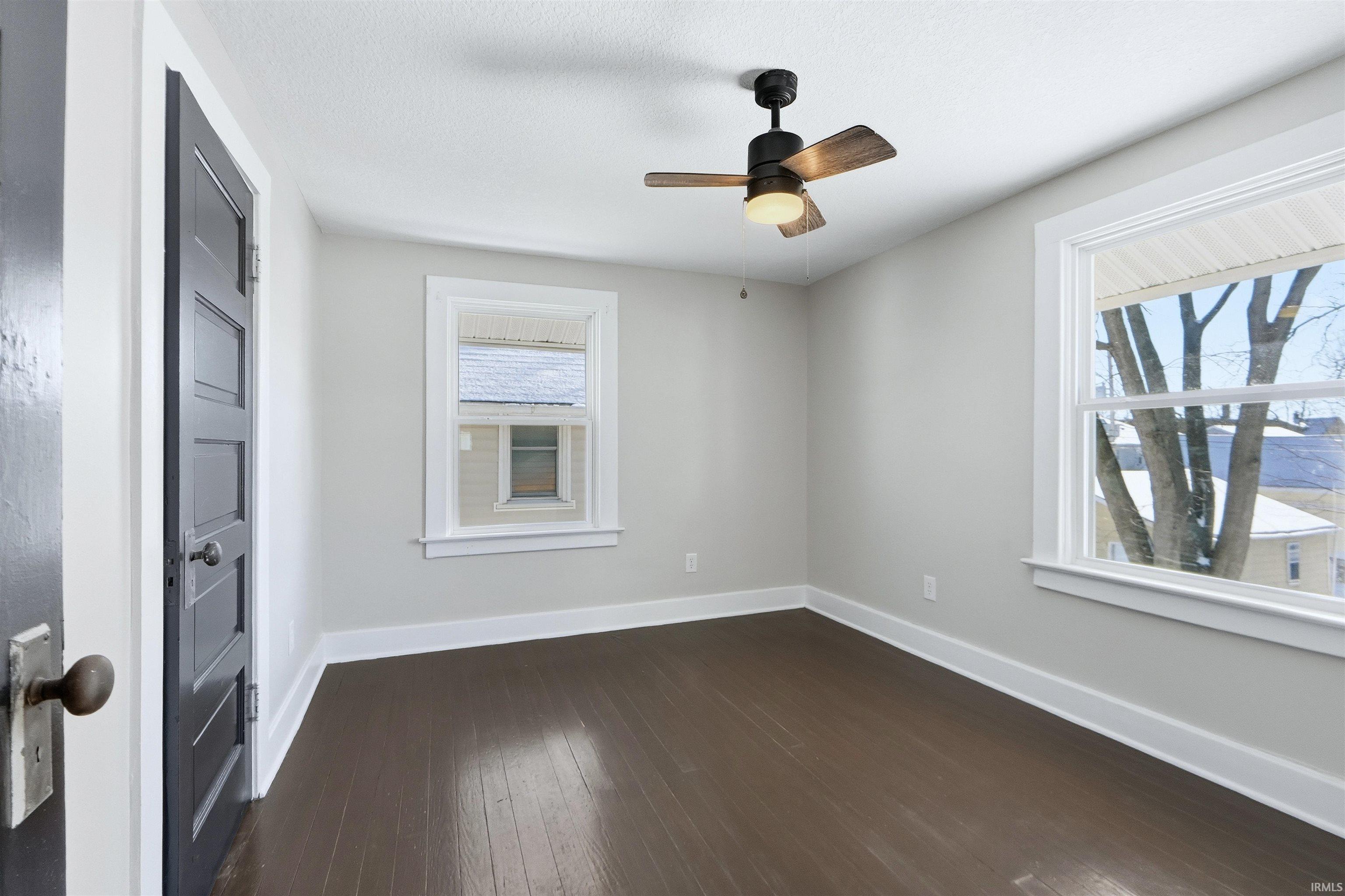 Unfurnished room with dark wood-style floors and ceiling fan