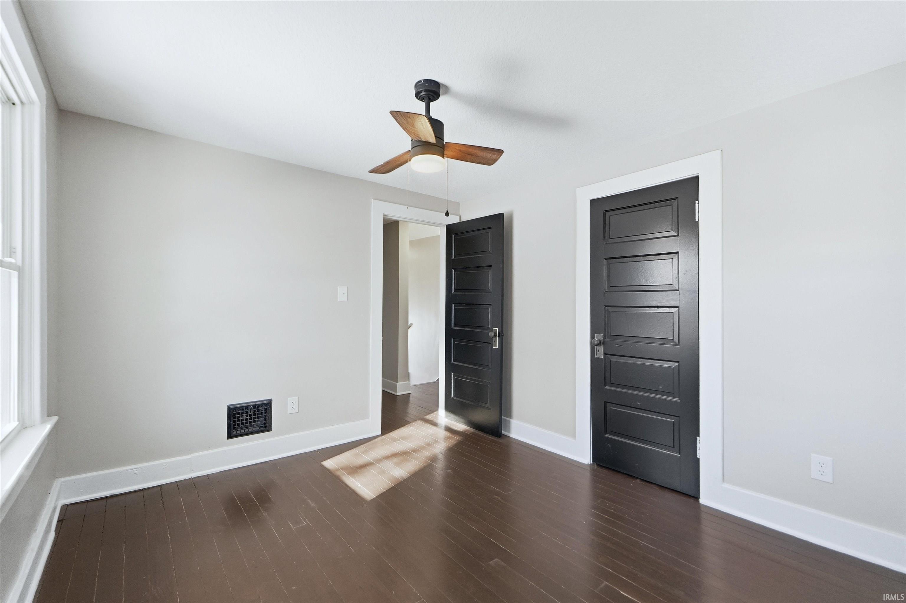Unfurnished bedroom featuring ceiling fan, dark wood-style flooring, and a closet