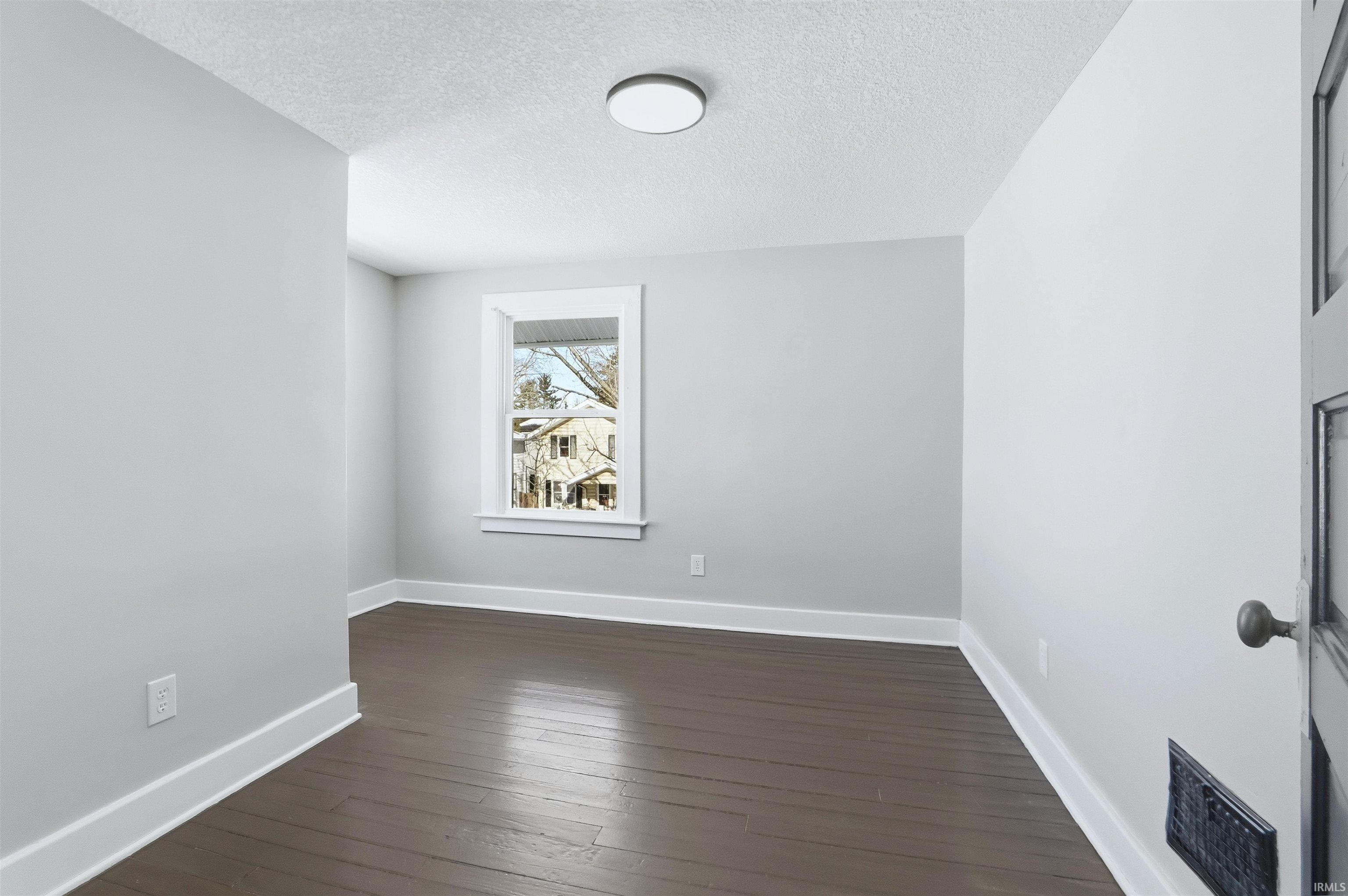 Spare room featuring a textured ceiling and dark wood-style floors