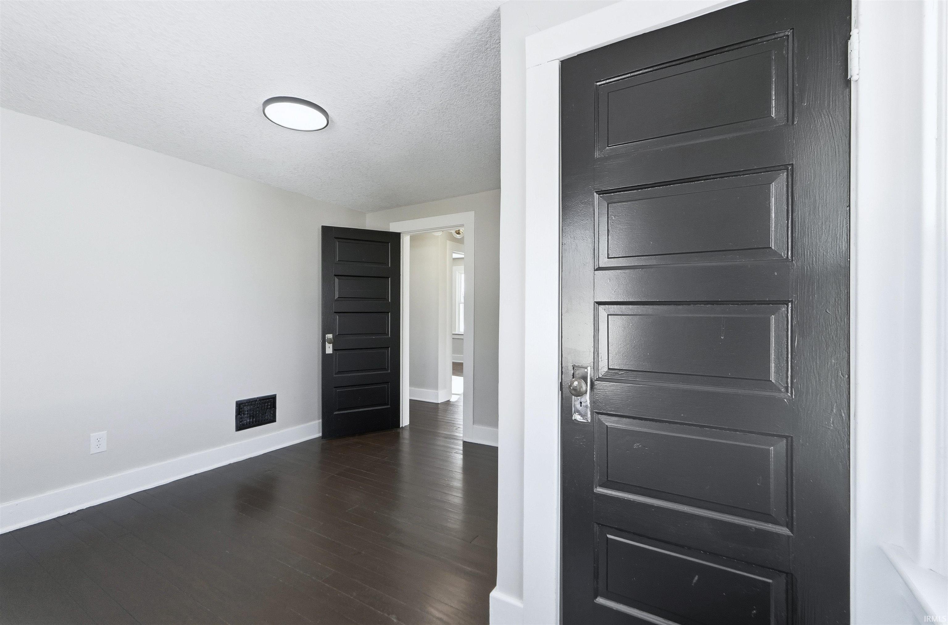 Unfurnished bedroom featuring dark wood finished floors and a textured ceiling