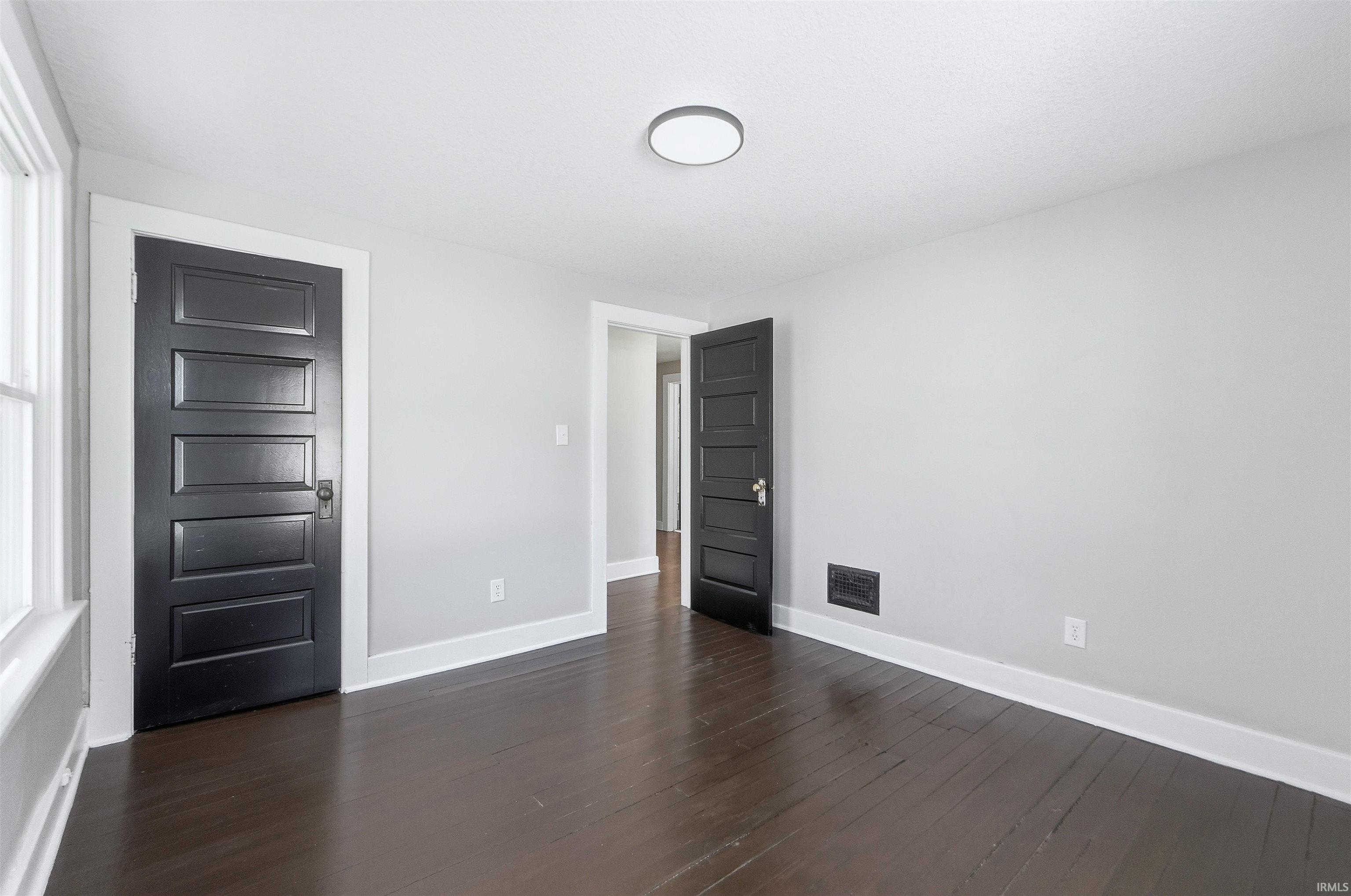 Unfurnished bedroom with baseboards and dark wood-style floors