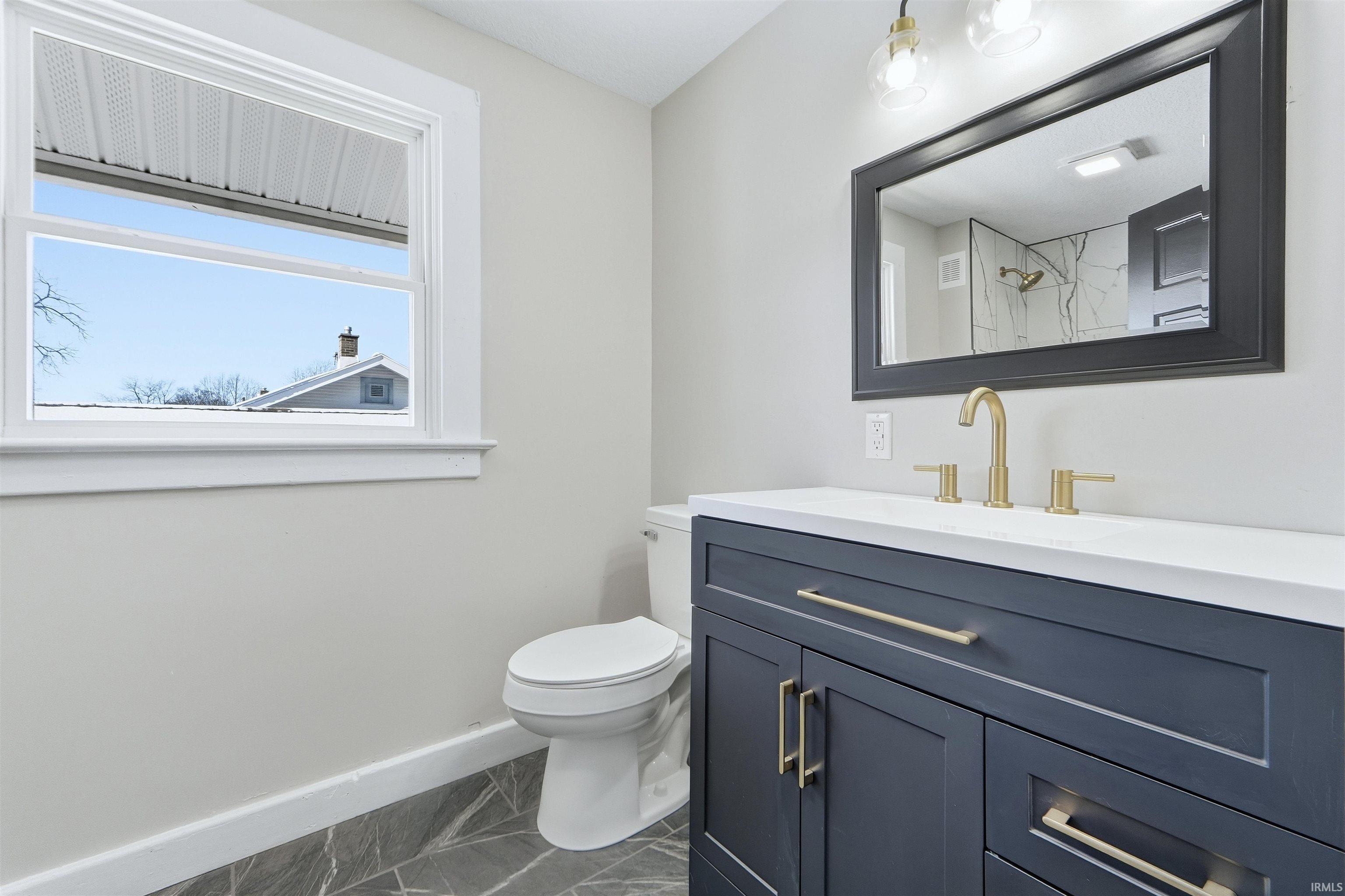 Bathroom featuring vanity, dark marble finish floors, and a shower