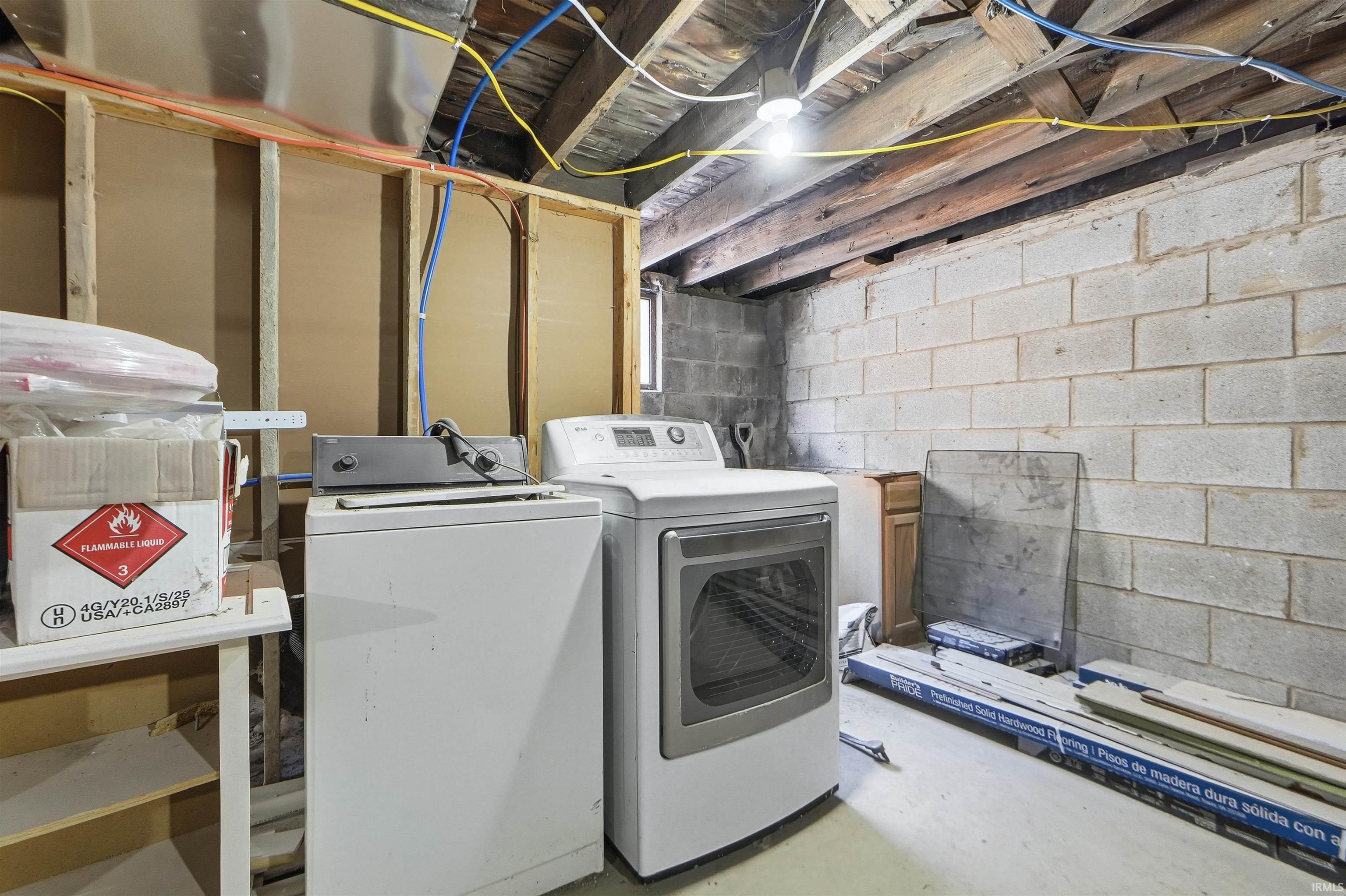 Laundry room with unfinished concrete flooring and washer and clothes dryer