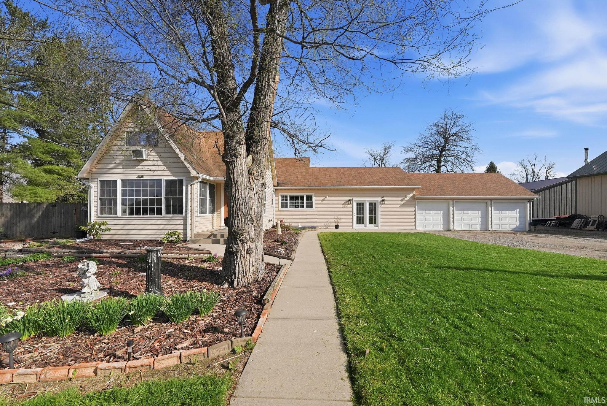 View of front of property featuring french doors, a front lawn, driveway, an attached garage, and a sunroom