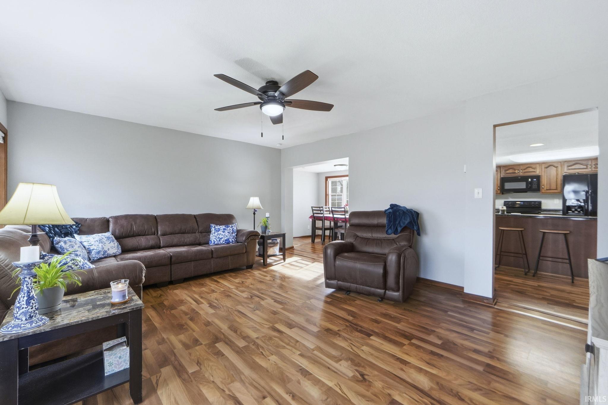 Living room with dark wood-style flooring and a ceiling fan