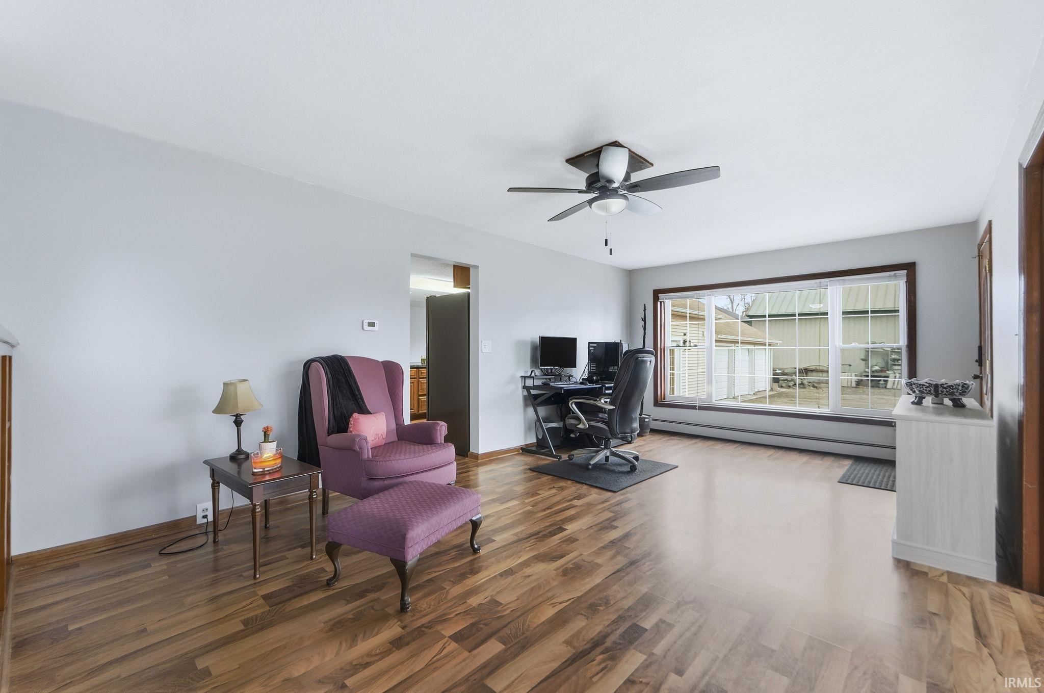Sitting room featuring a desk, a baseboard heating unit, wood finished floors, and ceiling fan