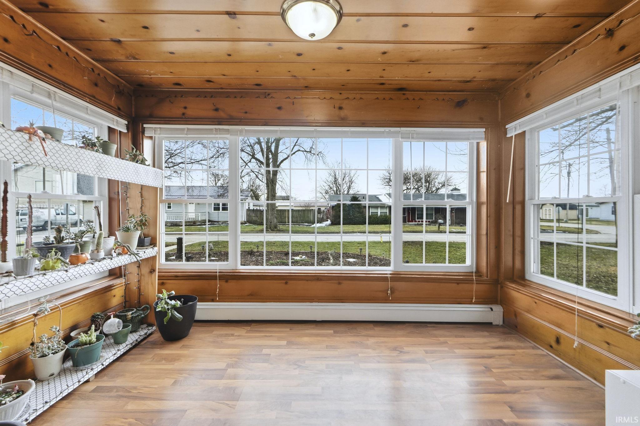 Unfurnished sunroom with wooden ceiling, a baseboard heating unit, and wood finished floors