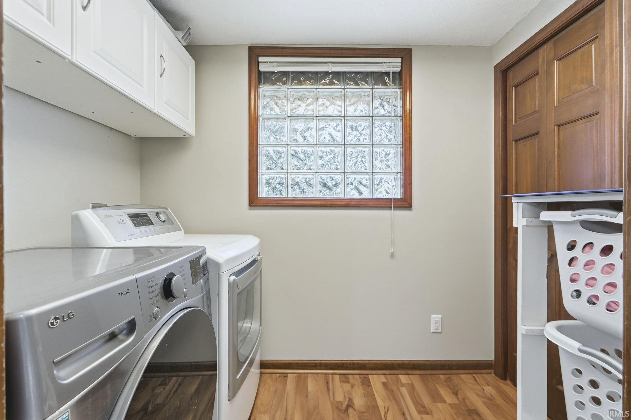 Washroom featuring light wood-type flooring, separate washer and dryer, and cabinet space