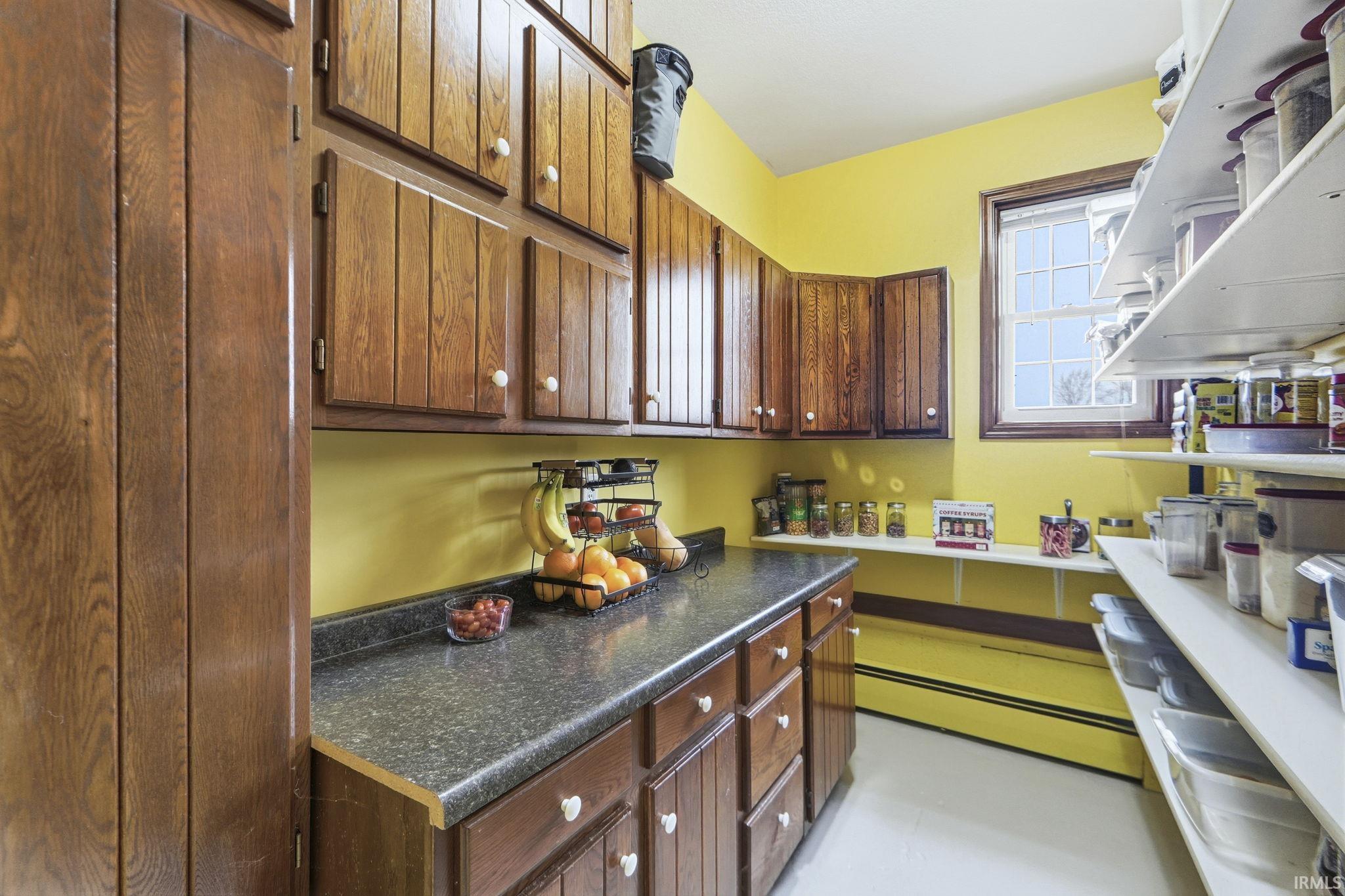 Kitchen with a baseboard heating unit, dark countertops, and dark brown cabinets