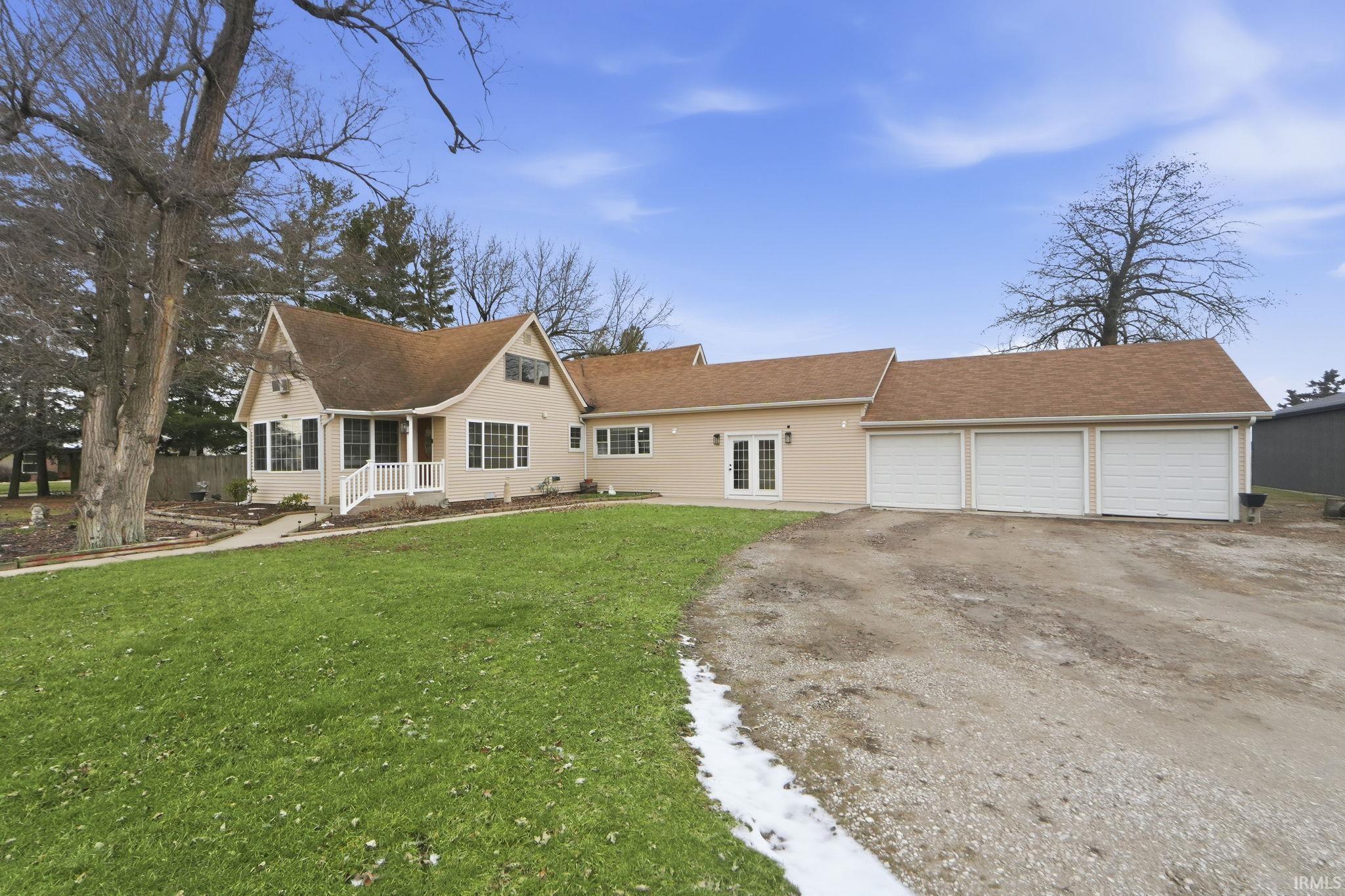 View of front of property featuring driveway, a front yard, a garage, and a shingled roof