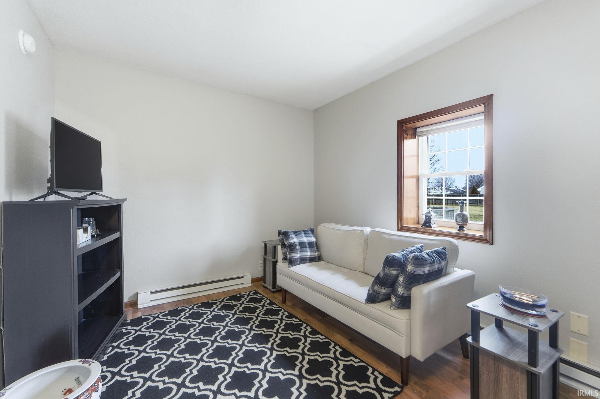 Living area with a baseboard radiator, a baseboard heating unit, and dark wood-style floors