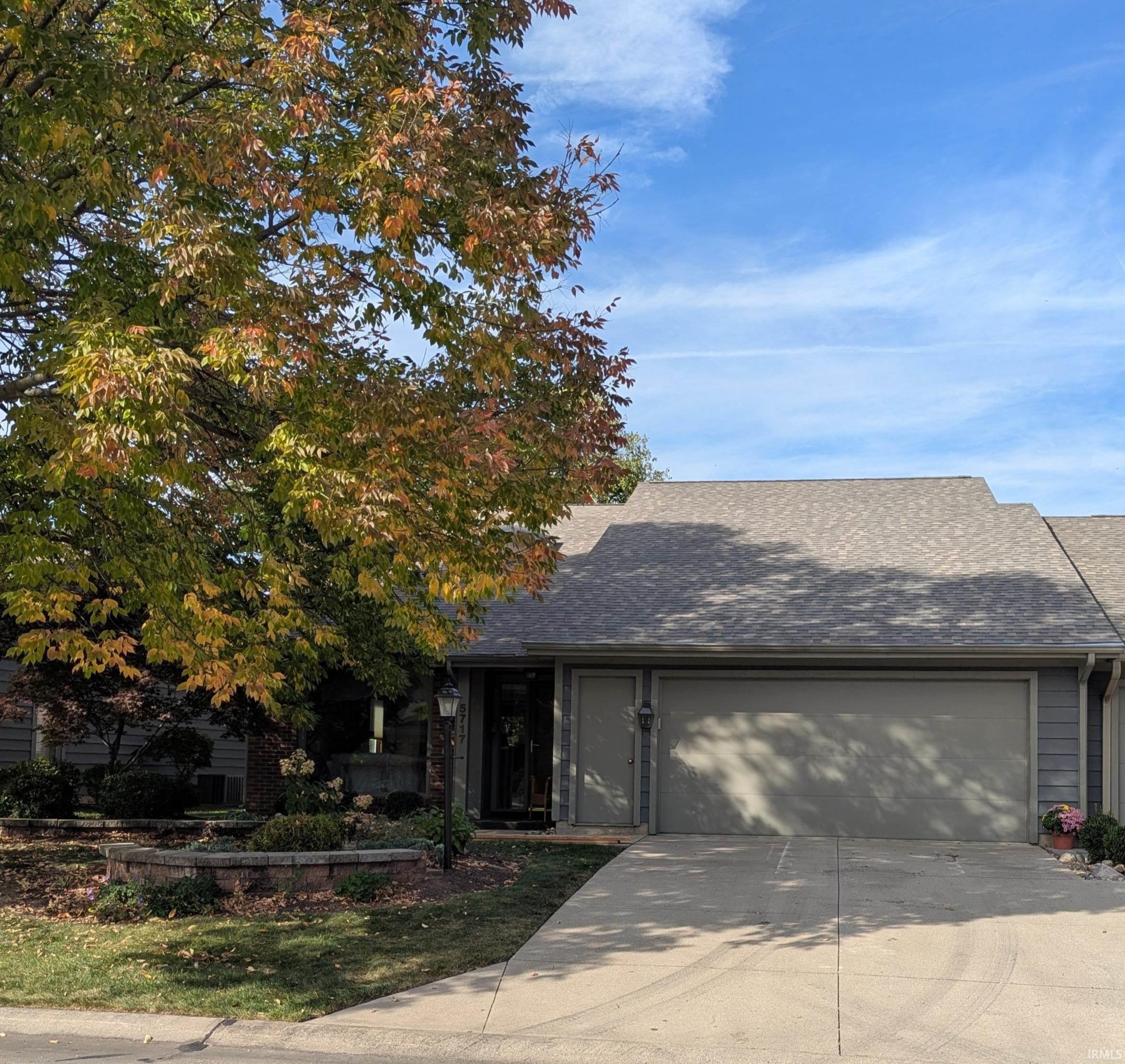 View of front of home featuring a garage, driveway, and a shingled roof