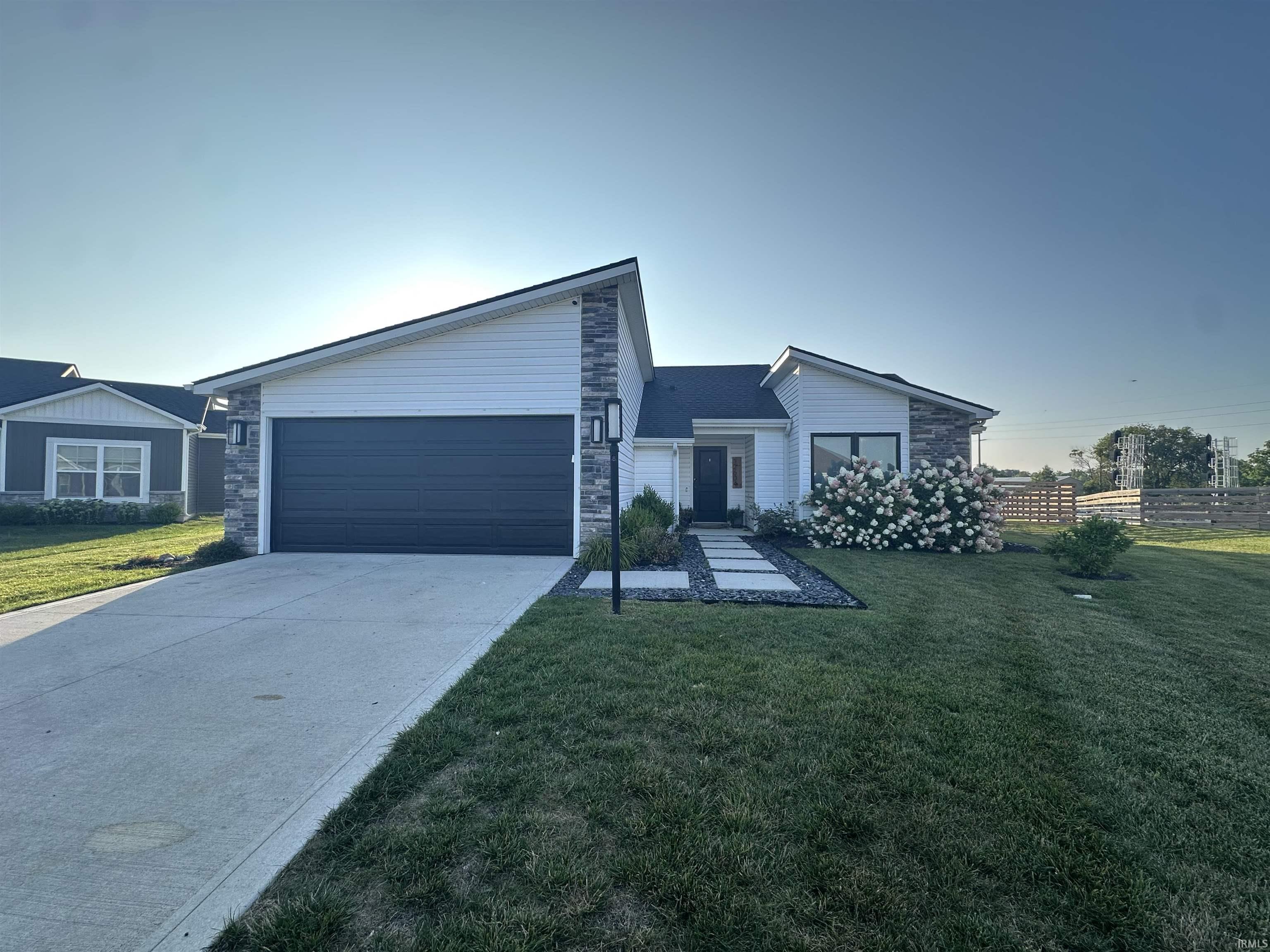 View of front of house featuring stone siding, driveway, a front yard, and a garage
