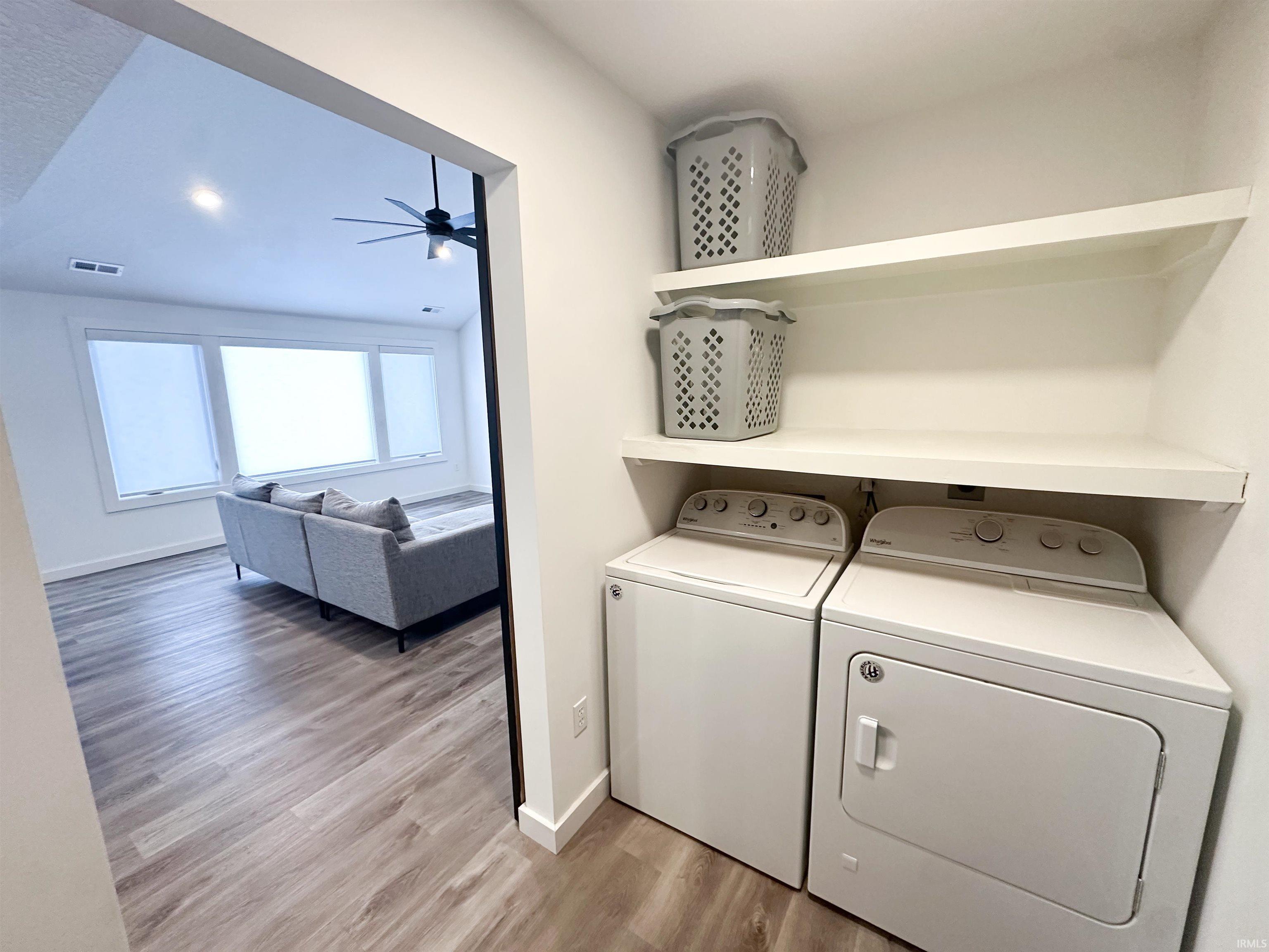 Laundry area featuring light wood-style flooring, ceiling fan, and separate washer and dryer