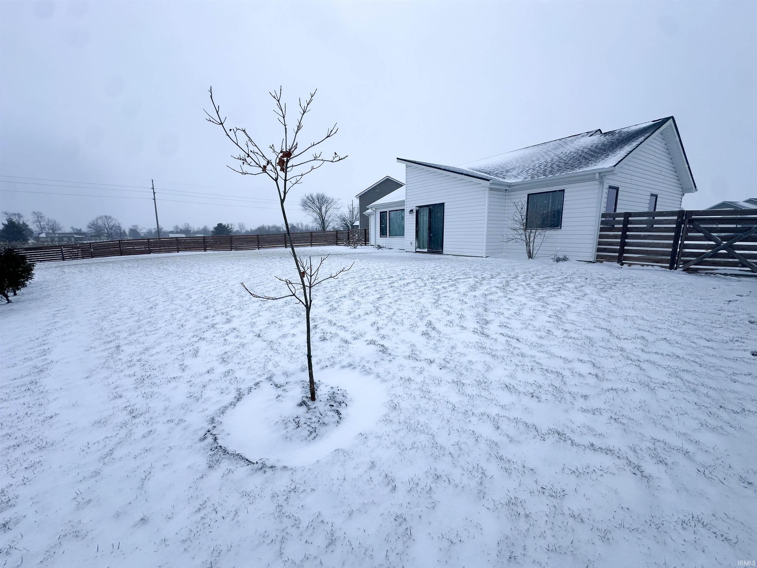 Yard covered in snow with a fenced backyard